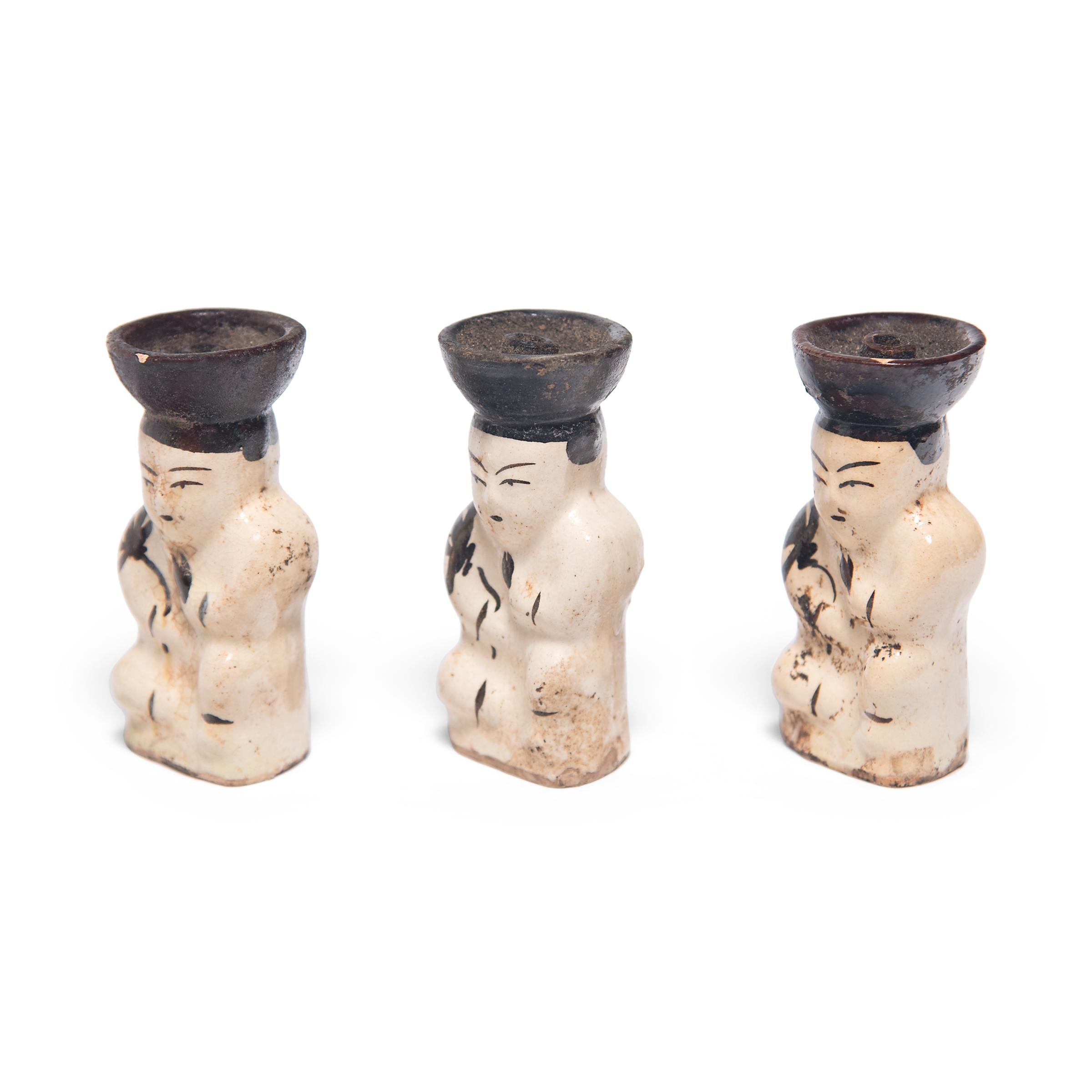 Each of these early 20th century ceramic oil lamps is formed in the shape of a young boy, a motif often referred to as a 