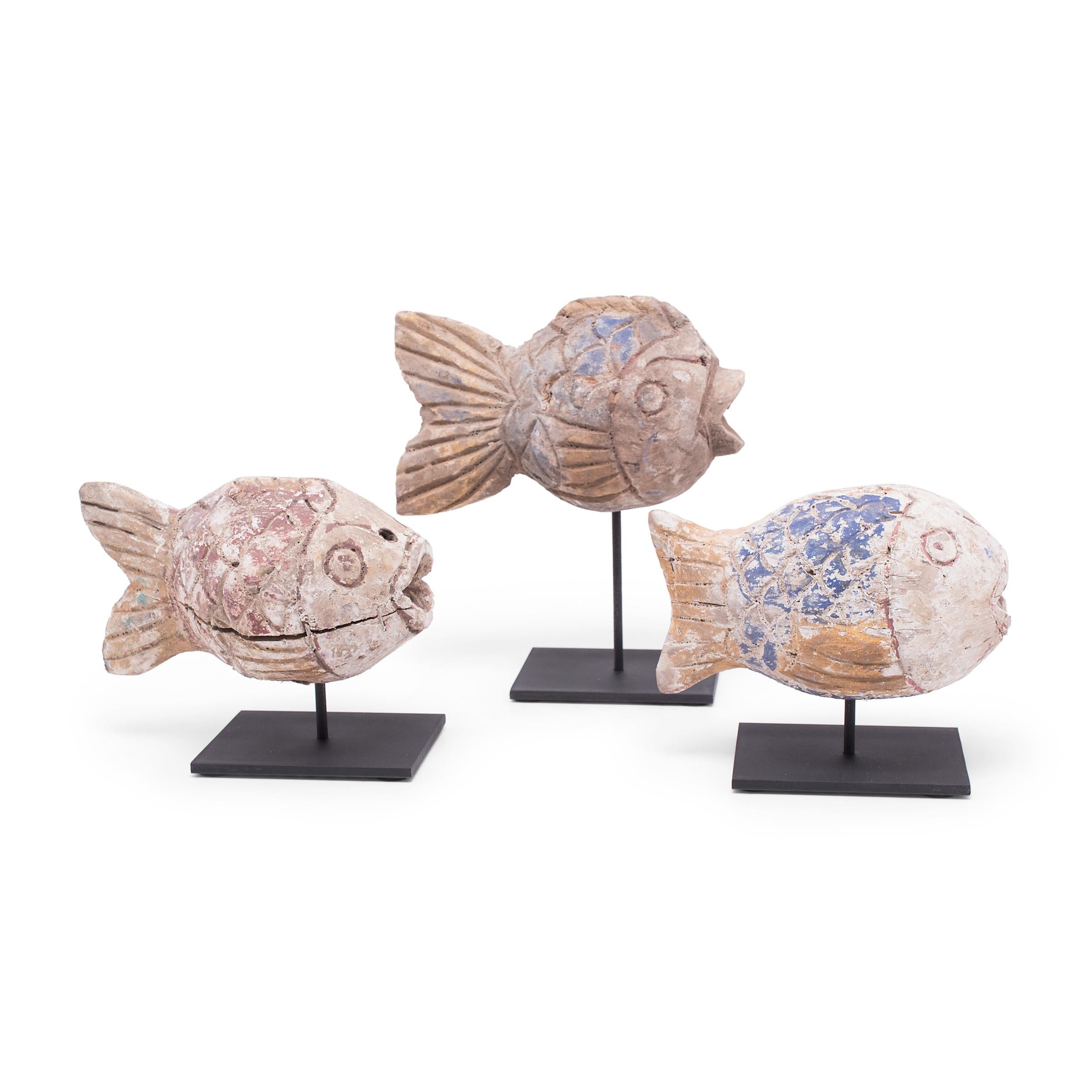 Hand-carved from reclaimed wood, these rustic fish sculptures recreate early 20th-century Chinese folk art designs. Each fish is painted with colorful pigments and finished with a beautifully worn texture. Common motifs in Chinese art, fish are