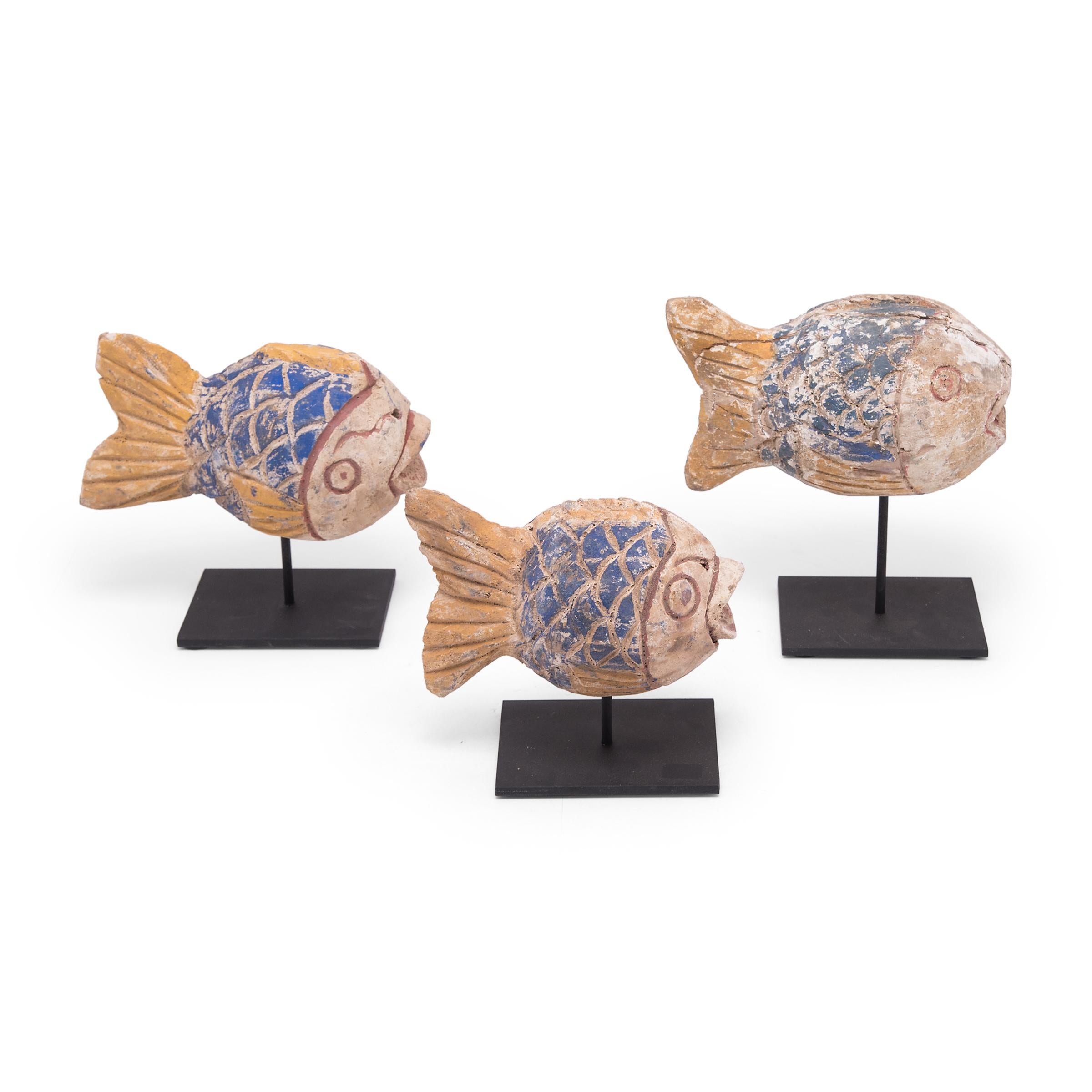 Hand-carved from reclaimed wood, these rustic fish sculptures recreate early 20th-century Chinese Folk Art designs. Each fish is painted with colorful pigments and finished with a beautifully worn texture. Common motifs in Chinese art, fish are