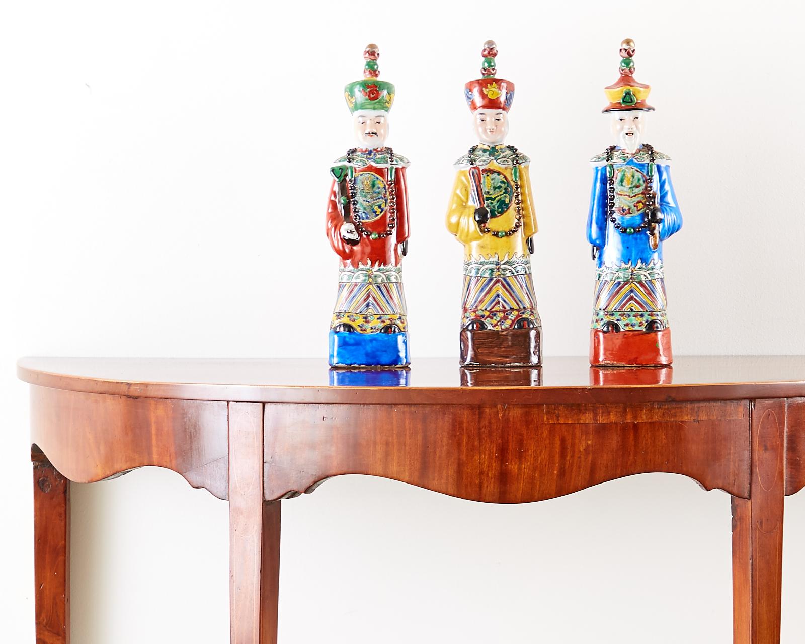 Colorful set of three Chinese porcelain Qing emperor, royal, and monarch figural group. Beautifully glazed with a wucai style having flamboyant robes and hats. Decorated with beaded necklaces with one holding a flute and the other a ruyi-head