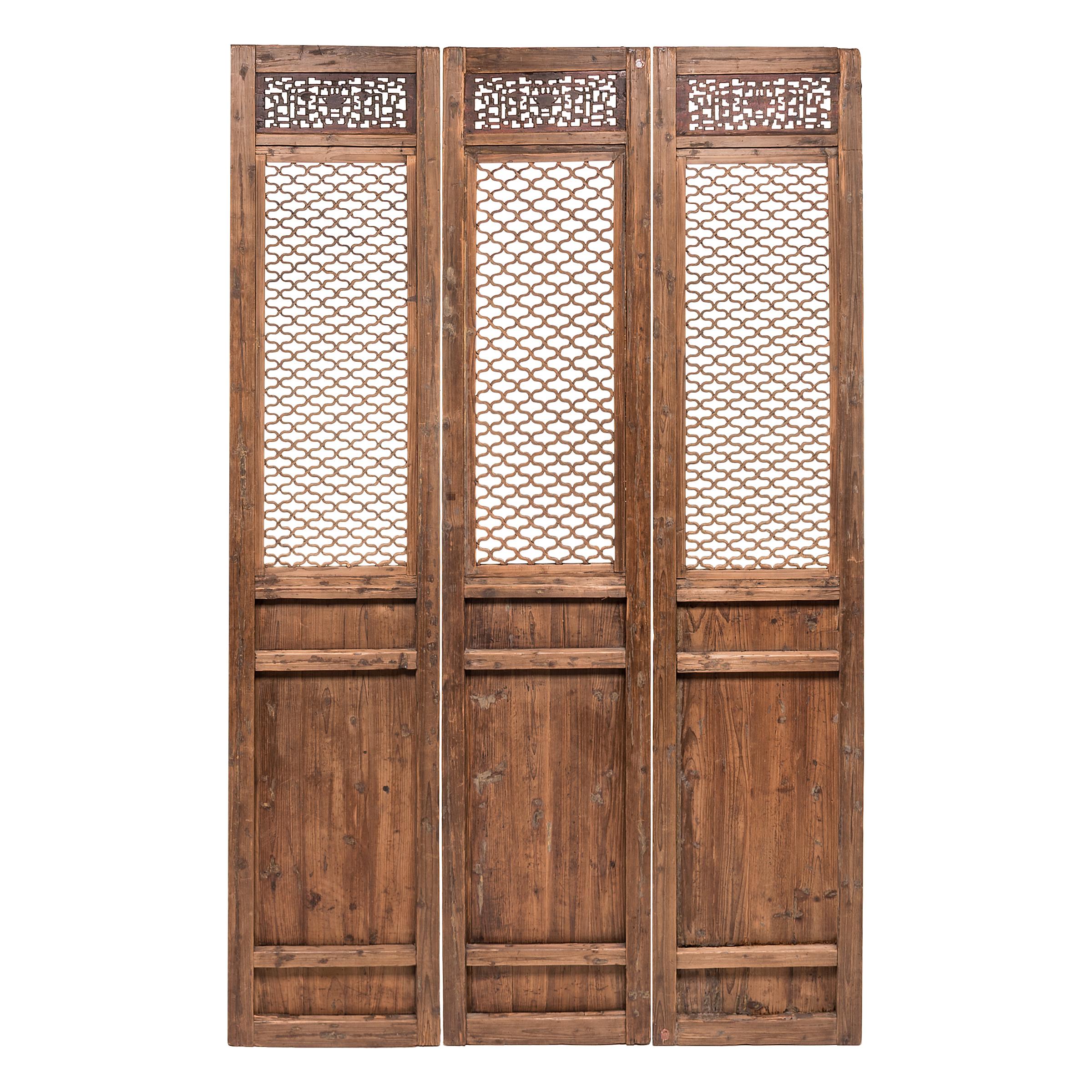 The sweeping elegance of these 19th-century courtyard doors, with their intricate lattice panels, hides the mathematical brilliance required to create them. The wax-finished, knotty panels evoke life in a traditional courtyard home, where the