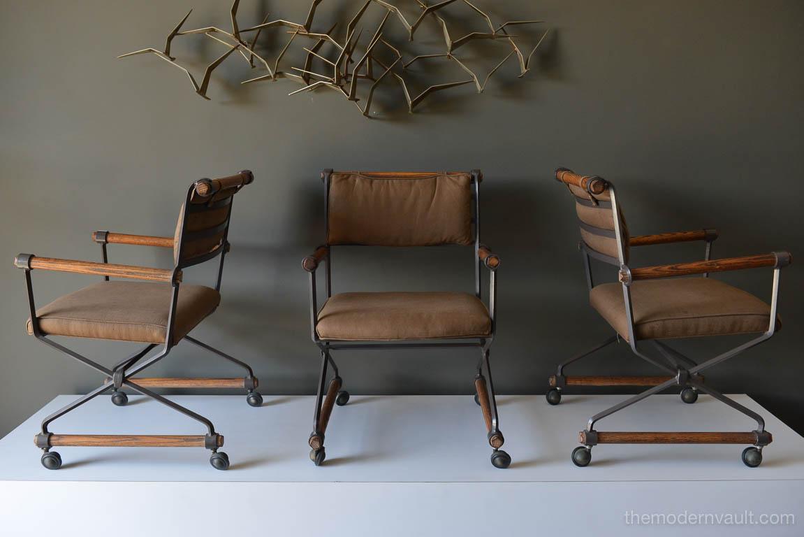 Set of Three Cleo Baldon Custom Iron and Oak Directors Chairs, circa 1970. Heavy wrought iron with oak wooden dowel armrests and bases. Casters glide very smooth and finished in a beautiful brown linen upholstery. Great for indoor or outdoor use.