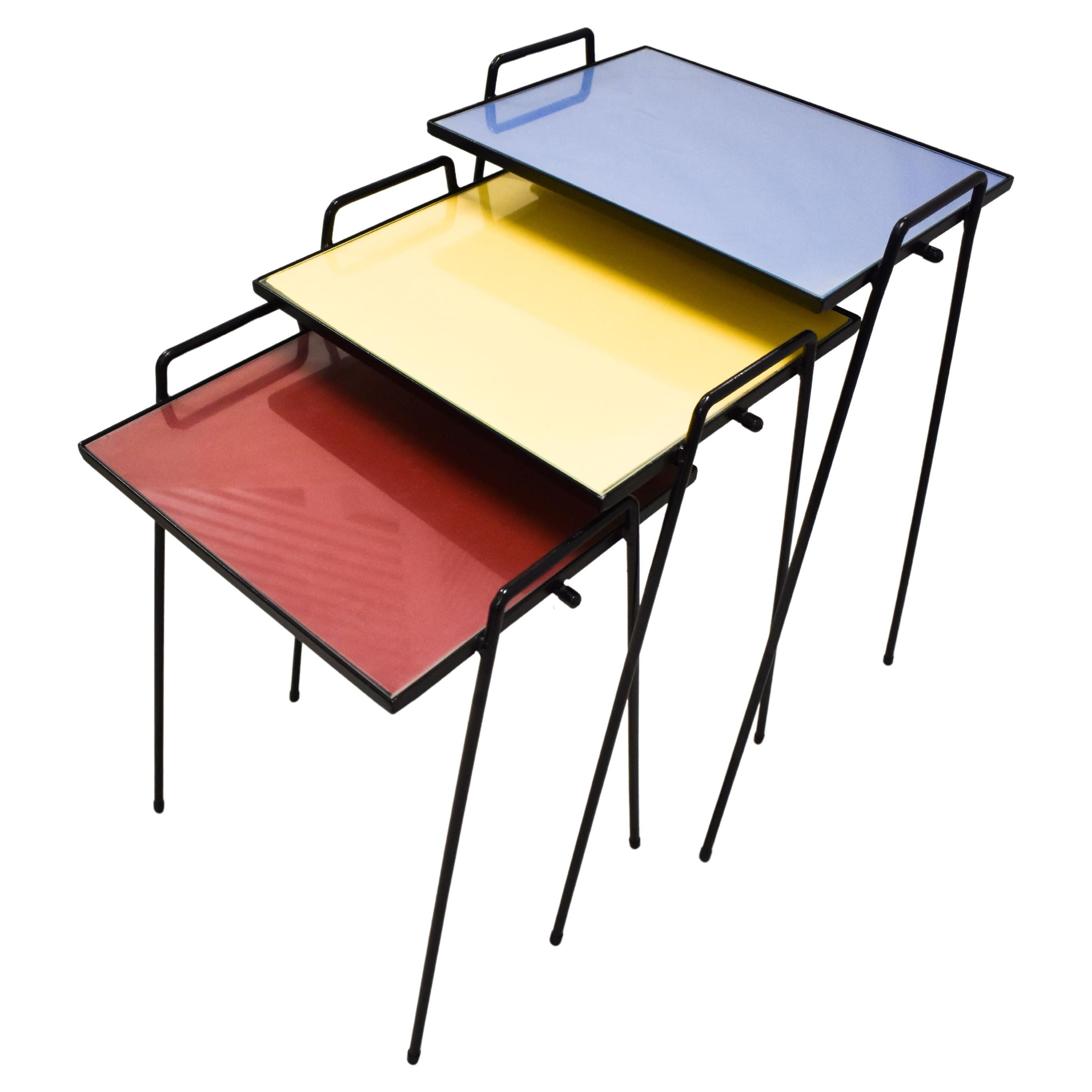 Ensemble de trois tables empilables colorées du milieu du siècle dernier, avec plateau en verre et pieds en fer