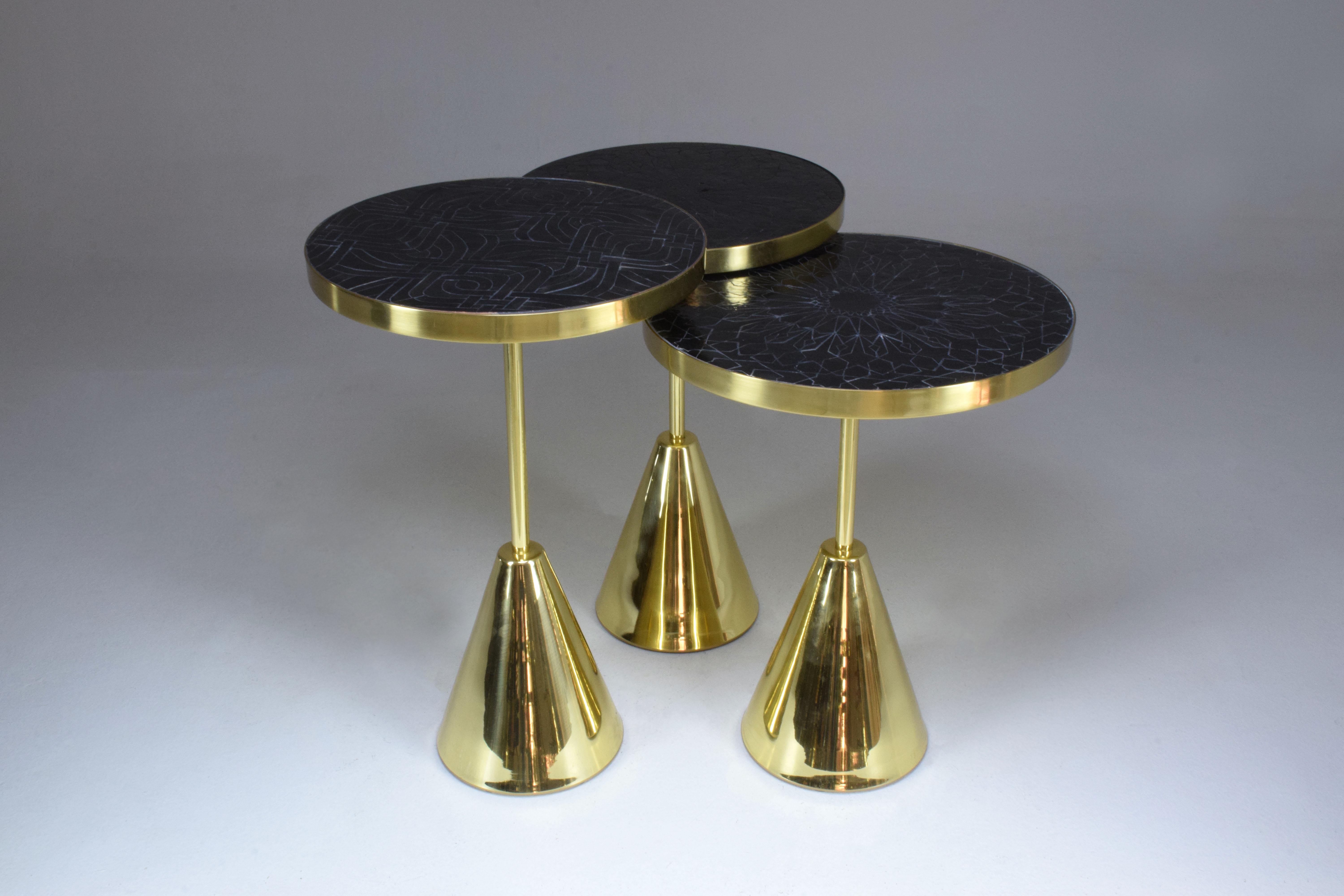 Set of three contemporary handcrafted guéridon side or end nesting tables composed of a solid brass structure and designed with two intricate mosaic tile tabletop zellige designs handmade with expert workmanship by Moroccan artisans. This set of