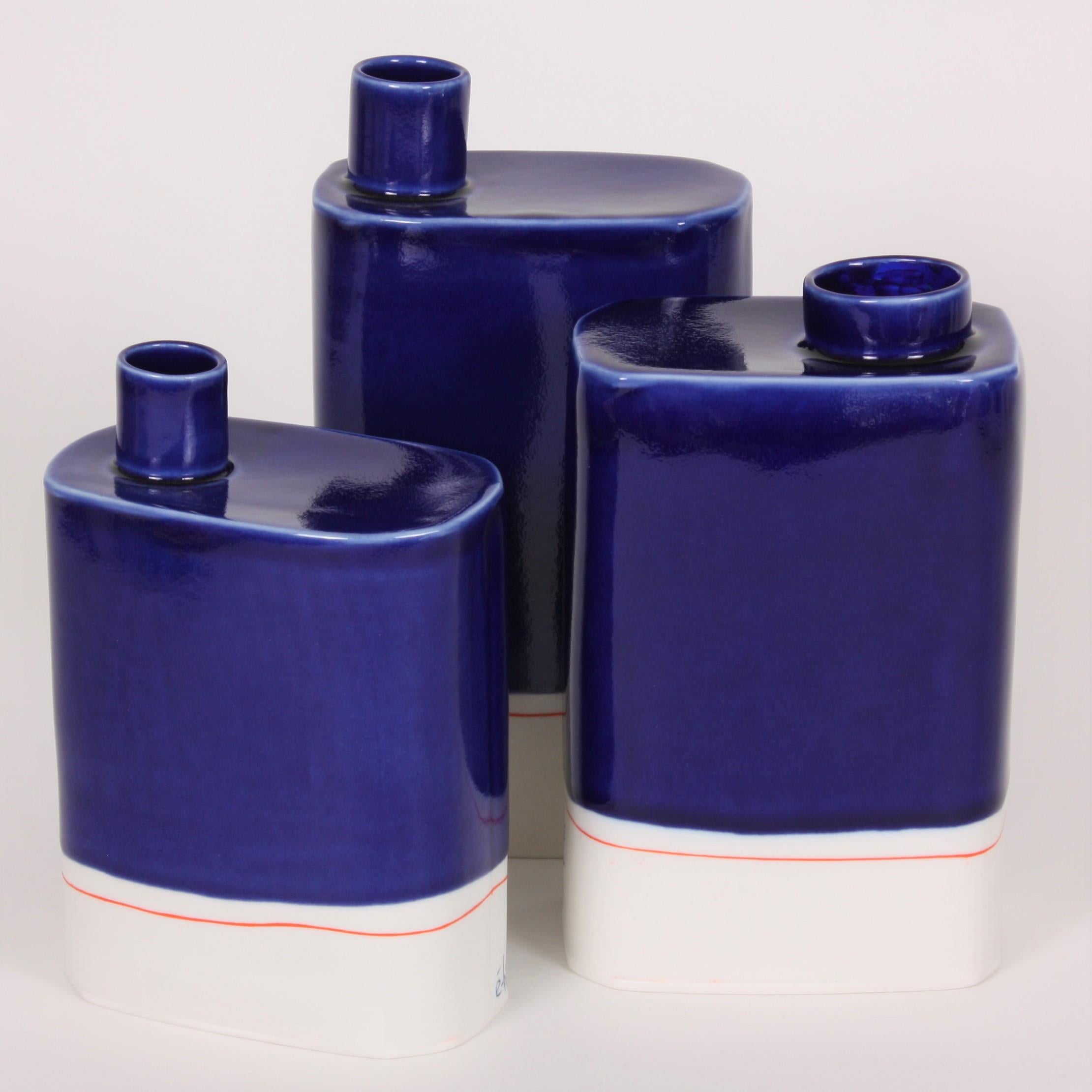 Set of three slab-built porcelain vases in the artist's signature cobalt blue. Well-known French ceramicist Eric Hibelot decorates his porcelain vessels with bold primary colors, in the pop art tradition. The artist sublimates today’s consumer