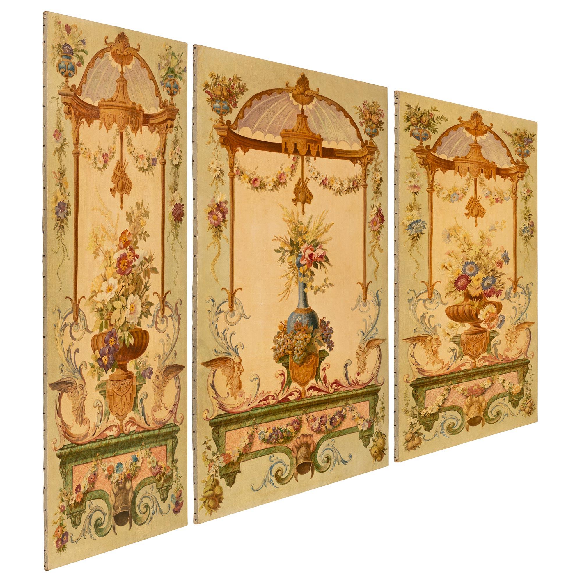 A striking and most elegant set of three Continental turn of the century Louis XVI st. hand painted decorative wall panels. Each rectangular panel displays beautiful finely detailed hand painted scrolled foliate designs and wonderful colorful