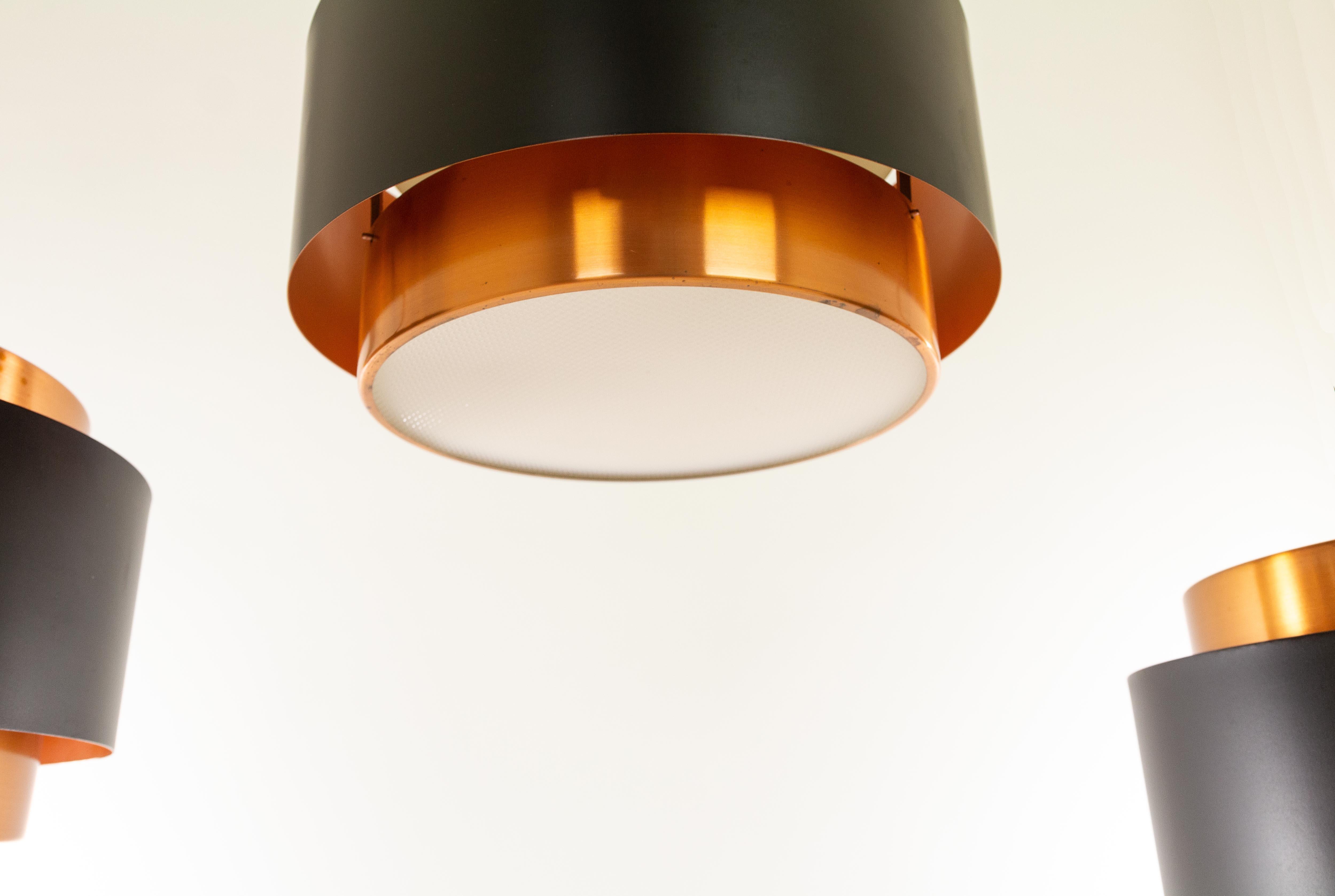 Unique set of three Saturn pendants, designed by Danish designer Jo Hammerborg and manufactured by Fog & Mørup.

The lamp is a structure of two concentric cylindrical copper bands that are held together by a black lacquered band. At the top and