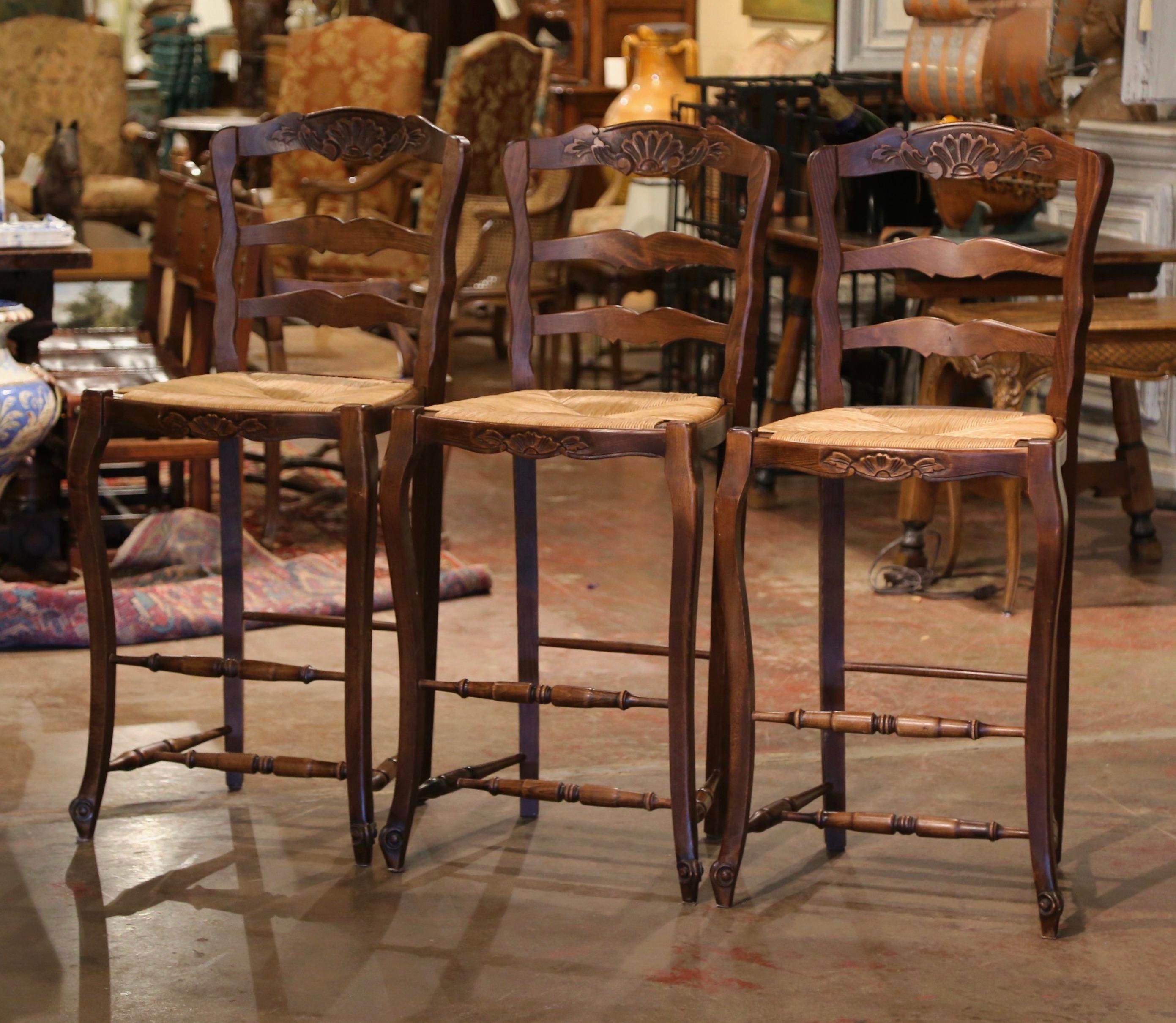 Dress a bar with this elegant set of vintage stools chairs. Hand carved from beech wood in Normandy France circa 1980, each chair stands on front cabriole legs ending with escargot feet, over a bottom stretcher; the chair features a scalloped apron