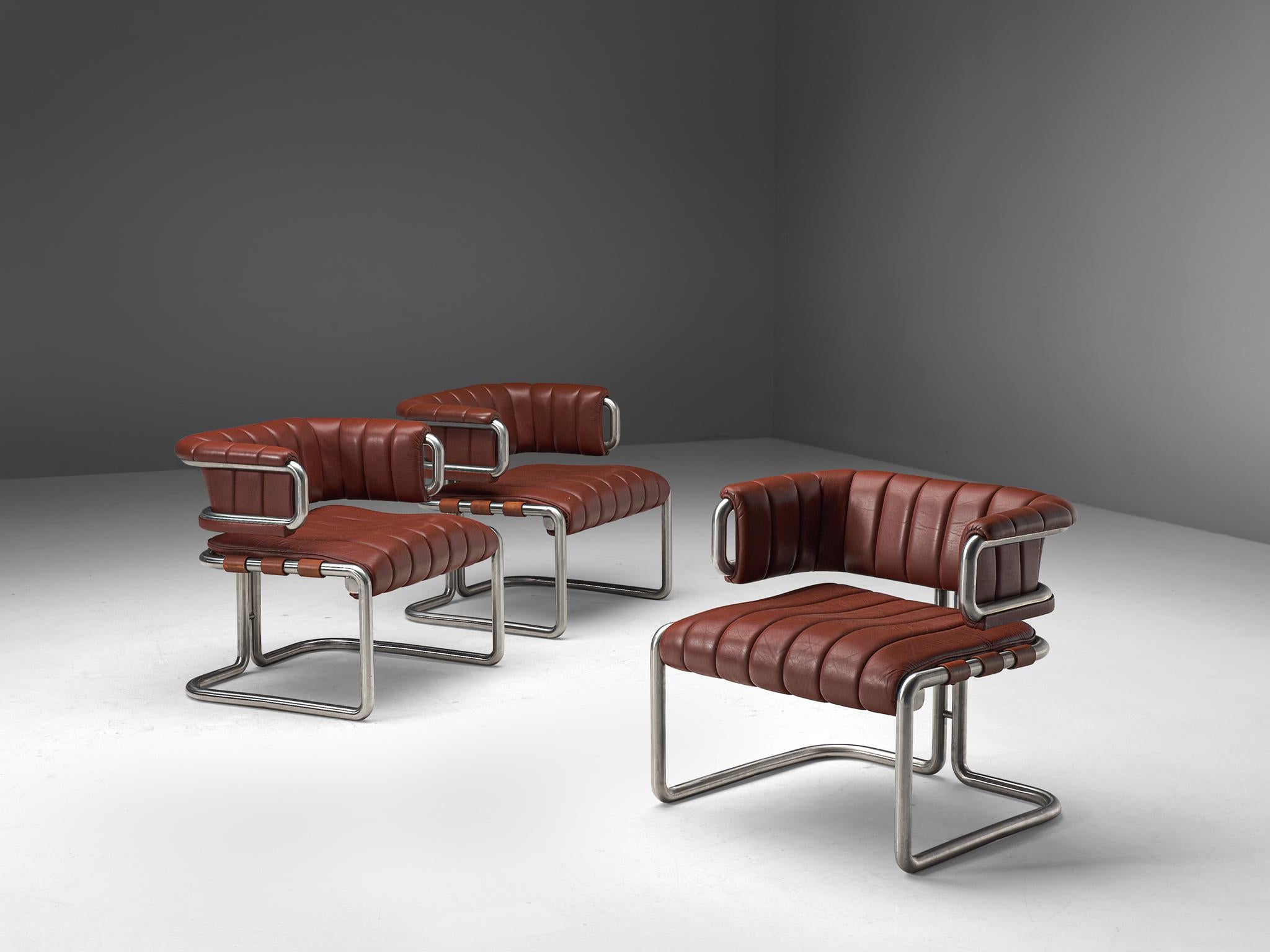 Set of three lounge chairs, leather and metal, Germany, 1960s

Set of three dark red leather chairs with metal tubular steel. This set is characterized by clear, straight lines that are noticeable in the leather as well. The frame of these chairs