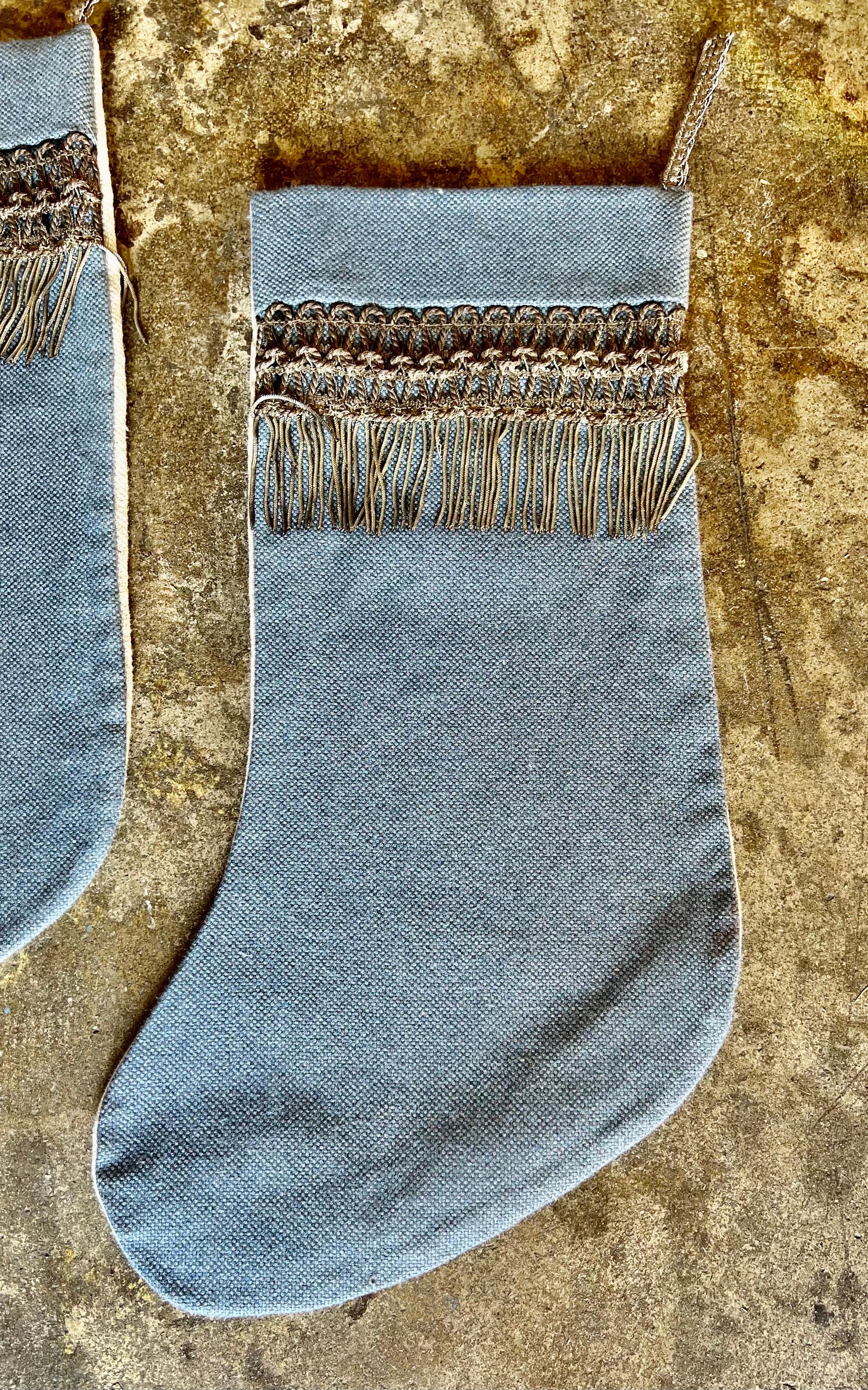 These three custom-made Christmas stockings featuring blue silk linen on the front, antique silver metallic 19th-century trims, and white linen backs is a sophisticated and timeless holiday accessory, blending rich textures and historical elements