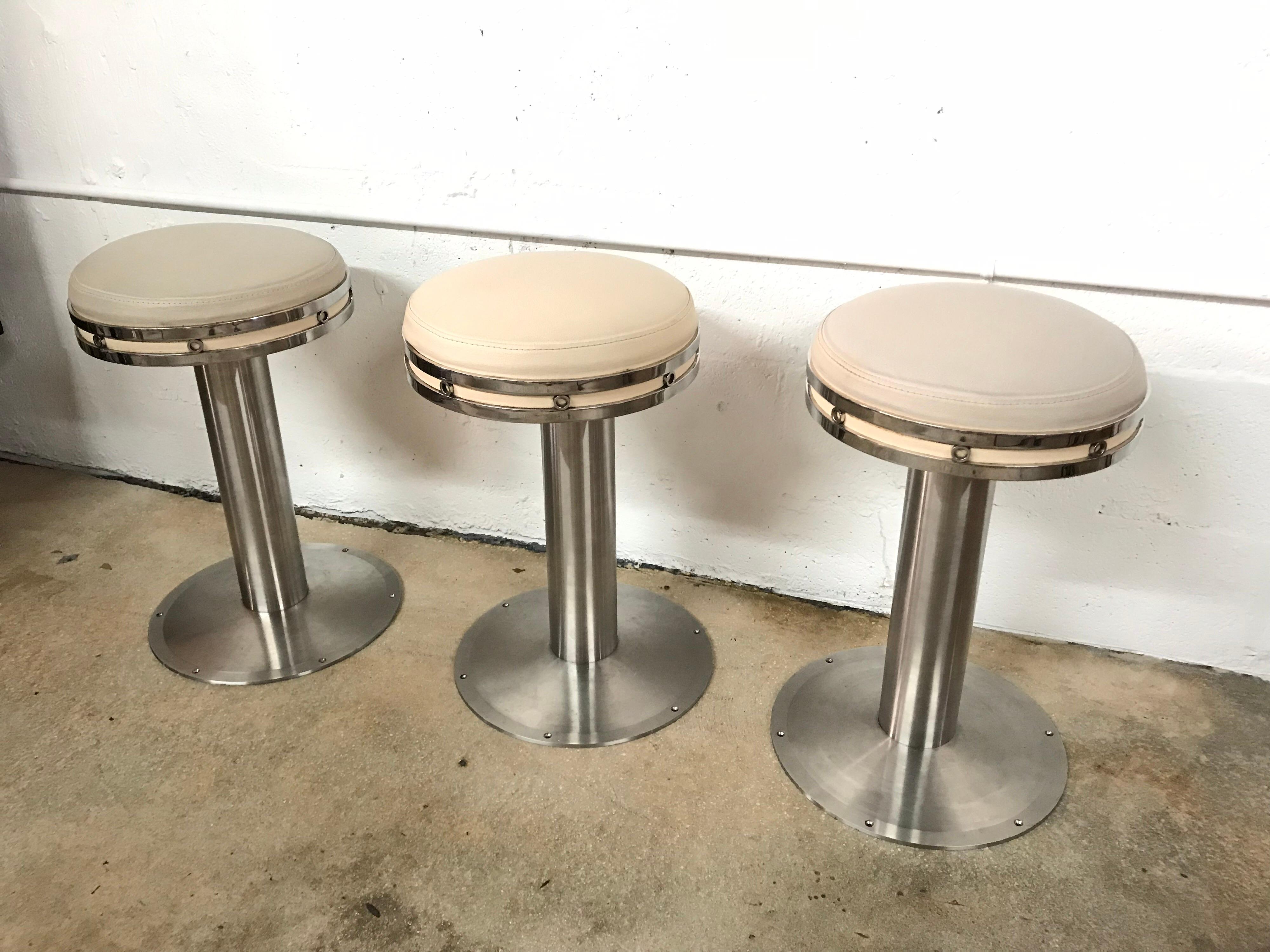 Karl Springer style custom stools, set of three, rendered in steel with leather upholstery, stools have ability to be screwed into floor for yacht or hospitality use.  One stool is swivel the other two are stationary, can make all stools stationary