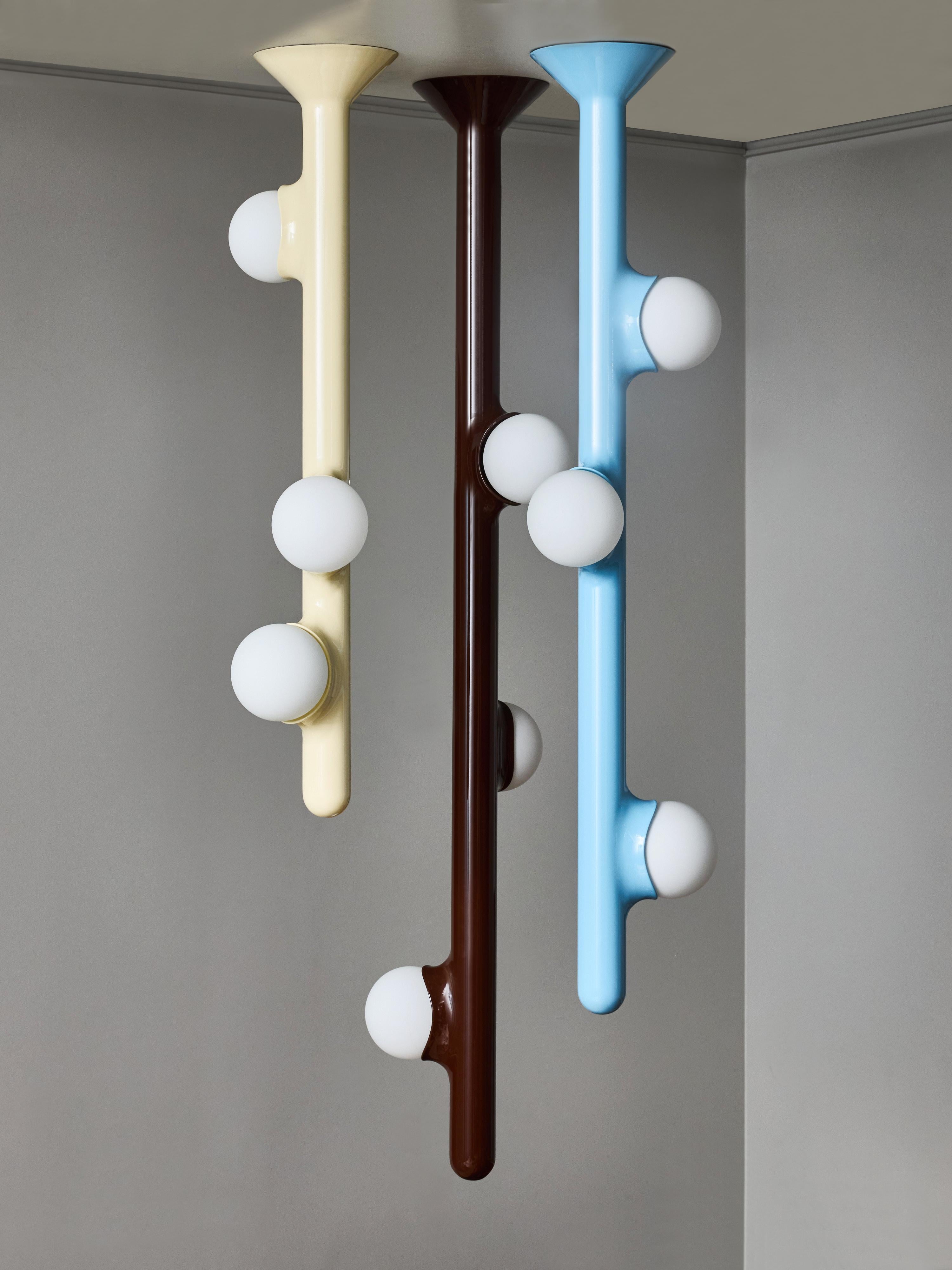 A striking set of three contemporary pendant lamps by Mickaël Koska, handcrafted in France. These sculptural fixtures are defined by their minimalist tubular silhouettes in painted metal, each punctuated by smooth opal glass globes that provide a