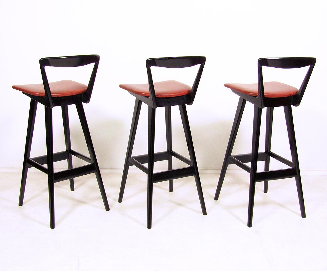 A set of three 1960s bar stools by Danish designer Rosengren Hansen for Brande Mobelindustri.

The graceful back supports and tapering legs put Hansen's bar stools amongst the best ever designed. 

These originally ebonised versions are