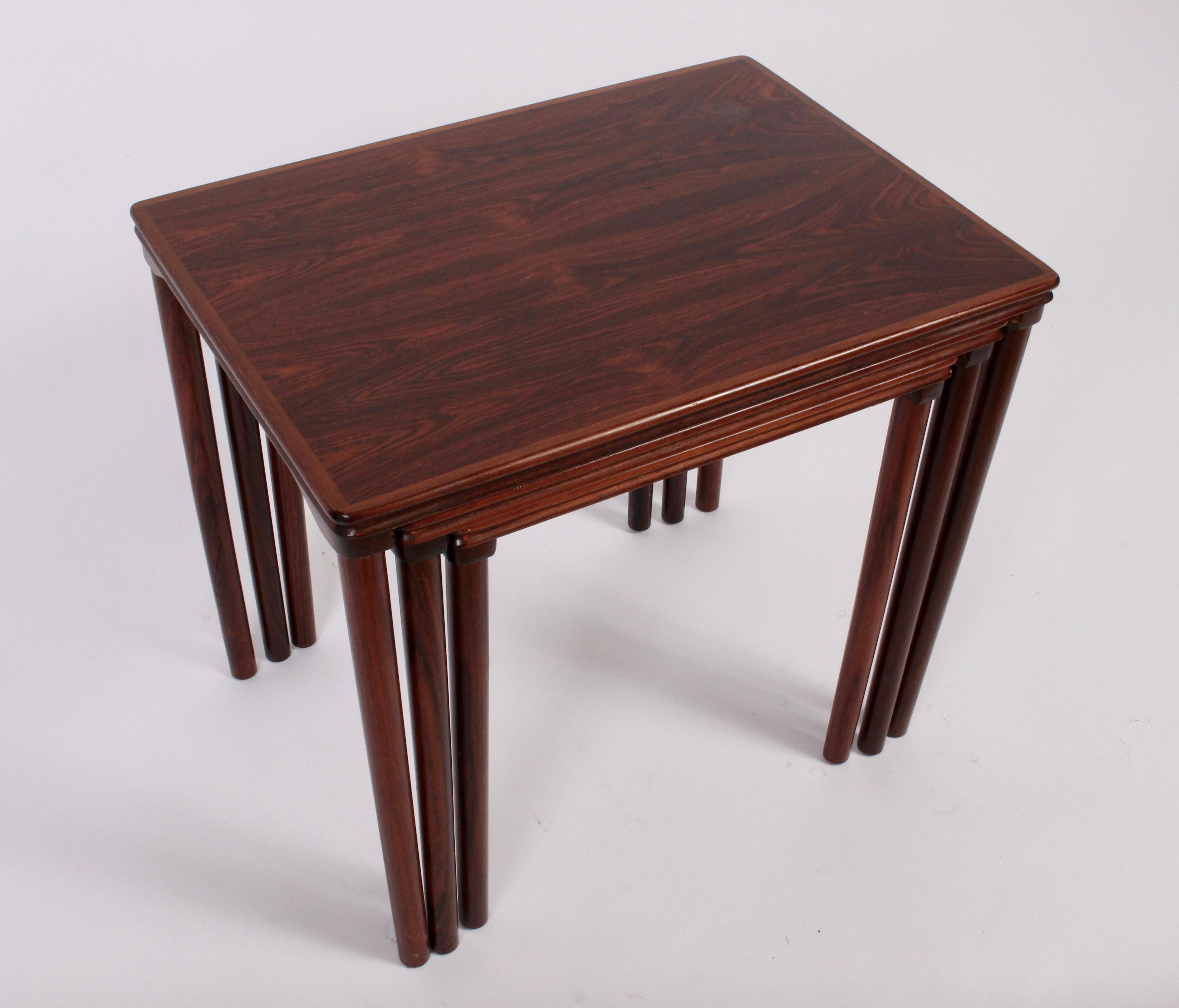 Set of 3 Scandinavian Modern Solid Rosewood Nesting Tables from the 1960's. Featuring three graduating tables with rounded corners. Exquisite grain.  Measurements: Outer Table: (19 H x 16 D x 21 W). Middle: (18 H x 15.5 D x 18 W). Lower: (17 H x