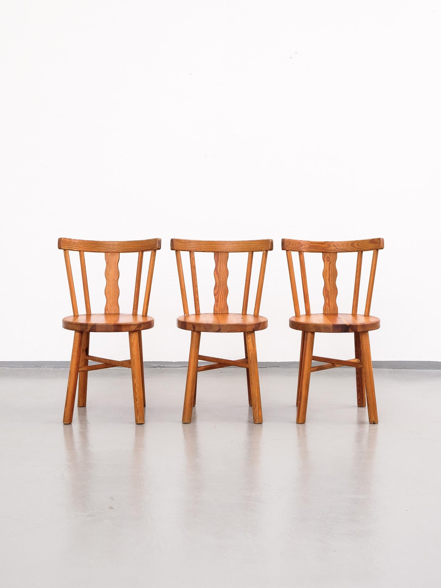 Set of three robust dining chairs in pine produced in Sweden.