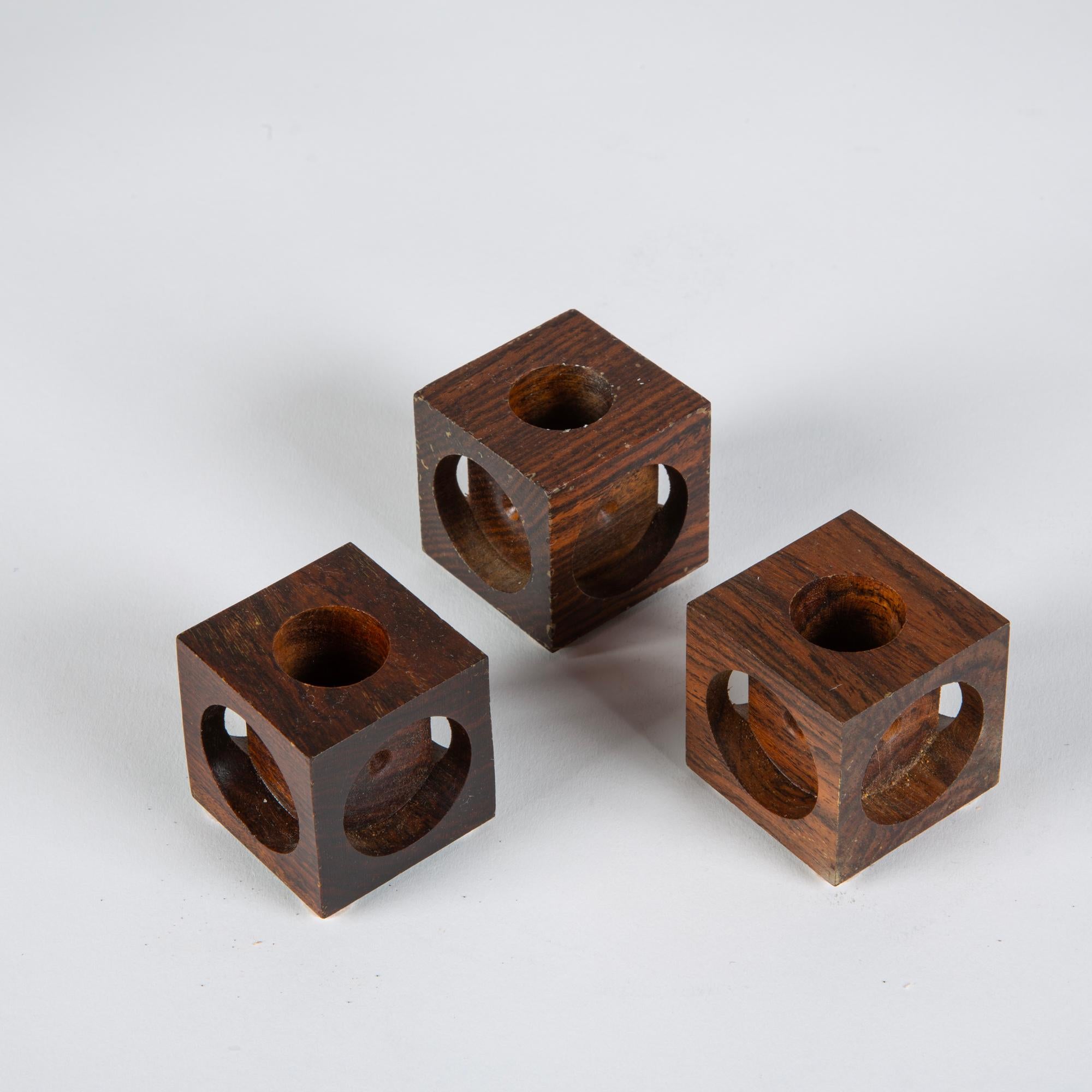 Ensemble de trois bougeoirs Don Shoemaker pour Señal en cocobolo. Les bougeoirs minimalistes en bois de rose, sculptés à la main, présentent un bloc géométrique avec des découpes circulaires sur chaque côté. Le sommet de chaque bloc comporte une