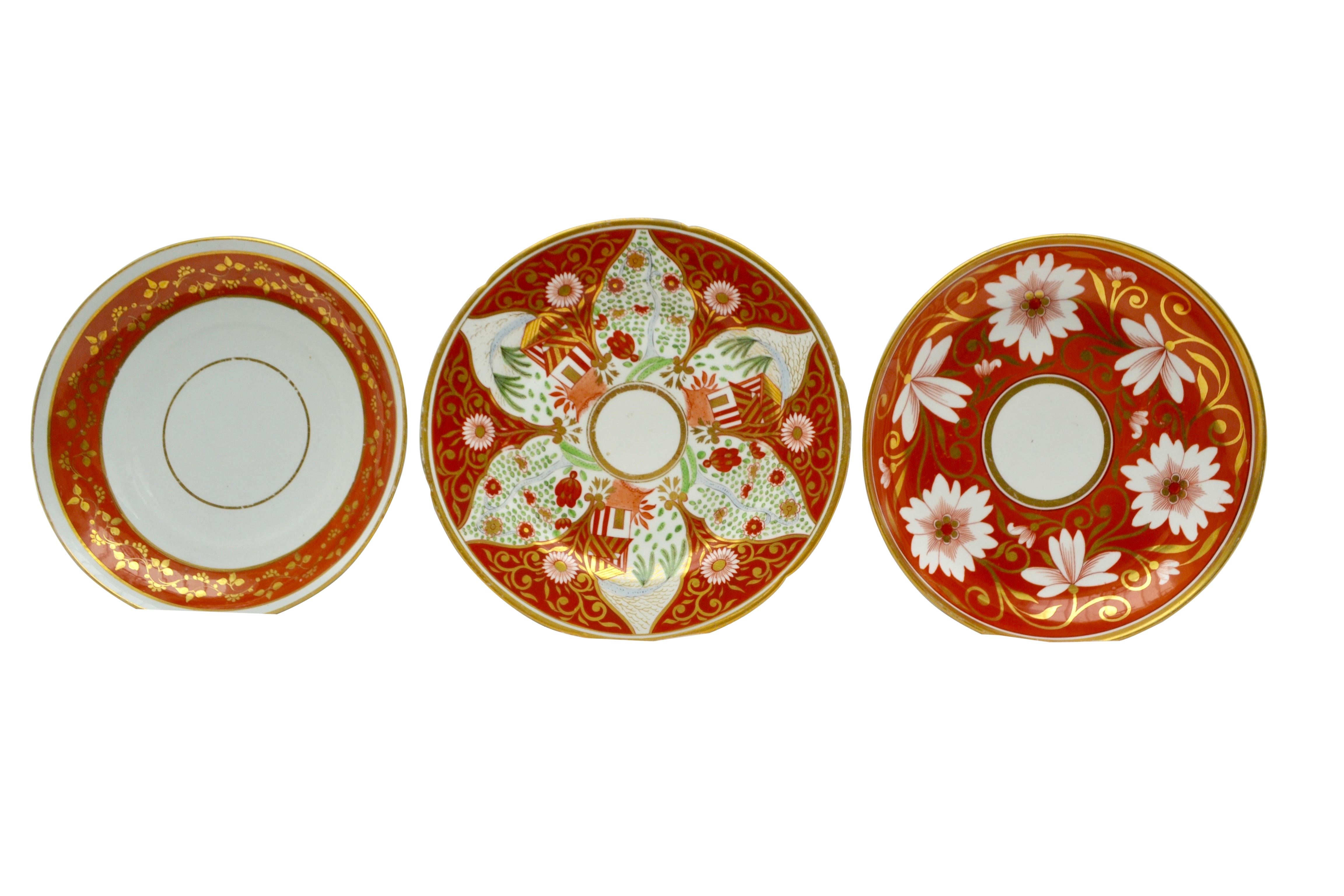 A set of three early 19th century English porcelain plates in mostly coral and gold hues. The left plate as seen in the photographs with an almost middle eastern pattern is Coalport measuring: 8.5