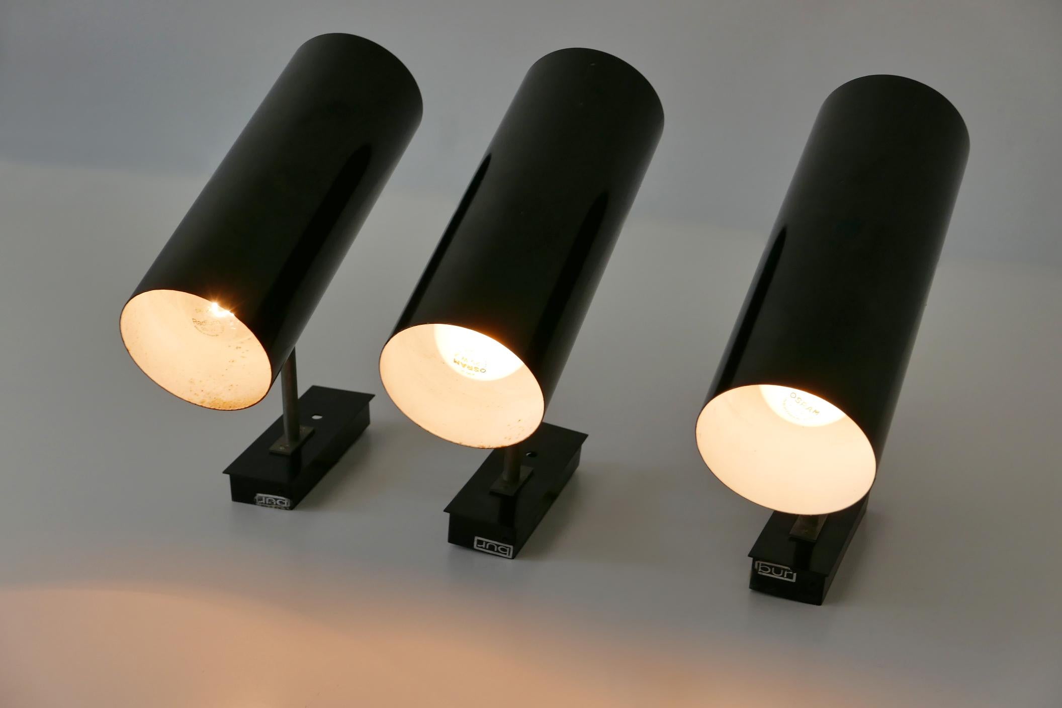 Set of three rare and elegant Mid-Century Modern sconces or wall lamps with adjustable shades. Manufactured by Bünte & Remmler (BuR), Germany, 1950s. Makers label to the base of each sconces (BUR).

Executed in outside black, inside white enameled