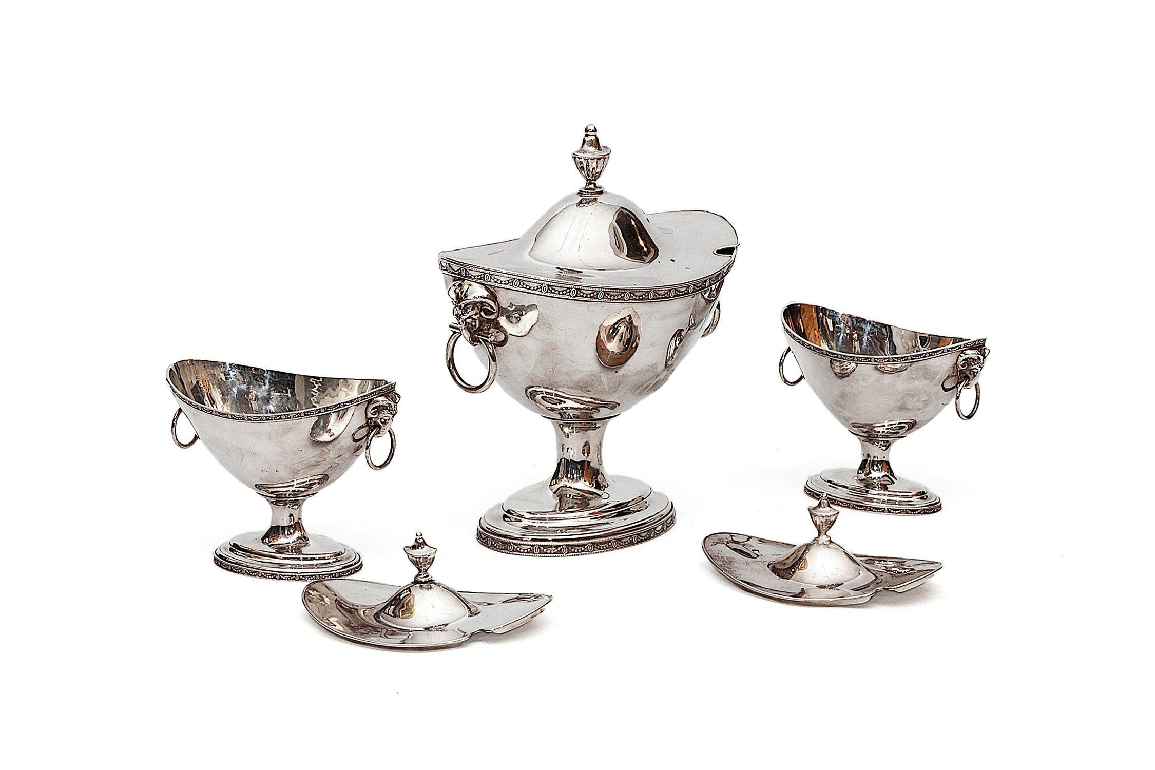These three Georgian boat-form sauce tureens are an exemplary Neoclassical set, each atop a spreading oval foot and with ring handles. The shaped lids are ornamented with urn-shaped finials.

One Large: 12