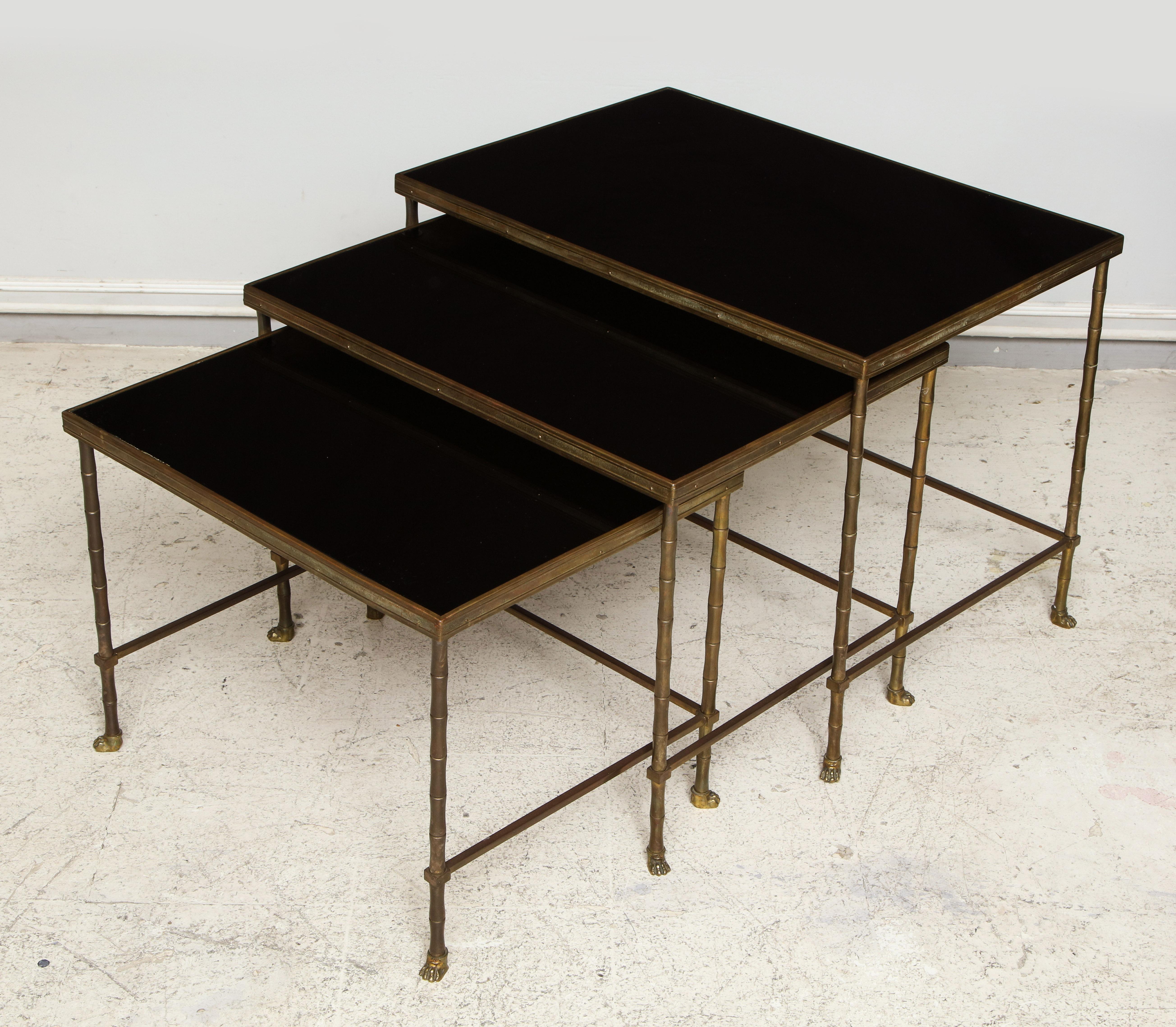 Set of three faux-bamboo brass nesting tables with smoked glass tops.