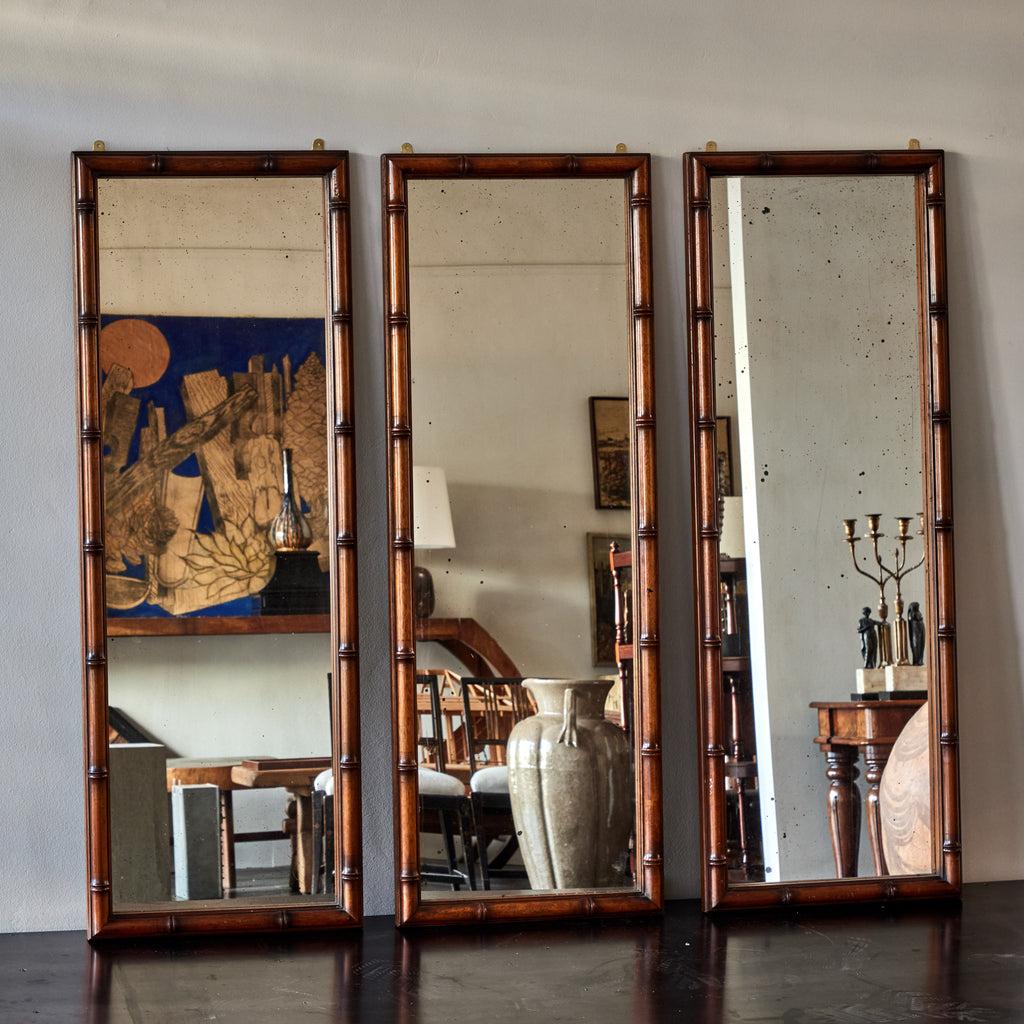 Set of three faux bamboo mirrors with original beveled plate glass from early 20th-century England. The thin mahogany frame been painted and carved with convincing delicacy. Arranged as a triptych, the set does an attractive job of breaking up