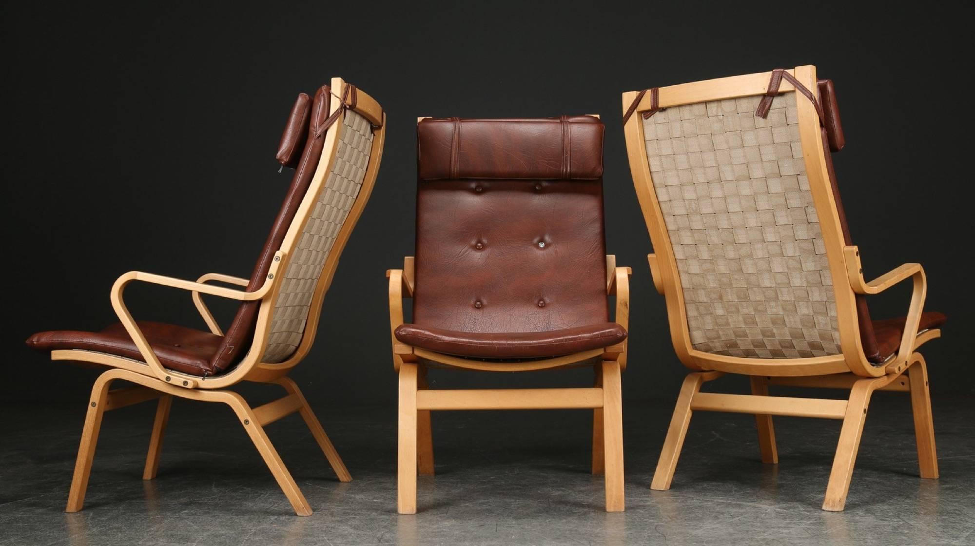 Three beechwood armchairs with form-bent beech frame, covered with brown leather. Comes with matching beech coffee table