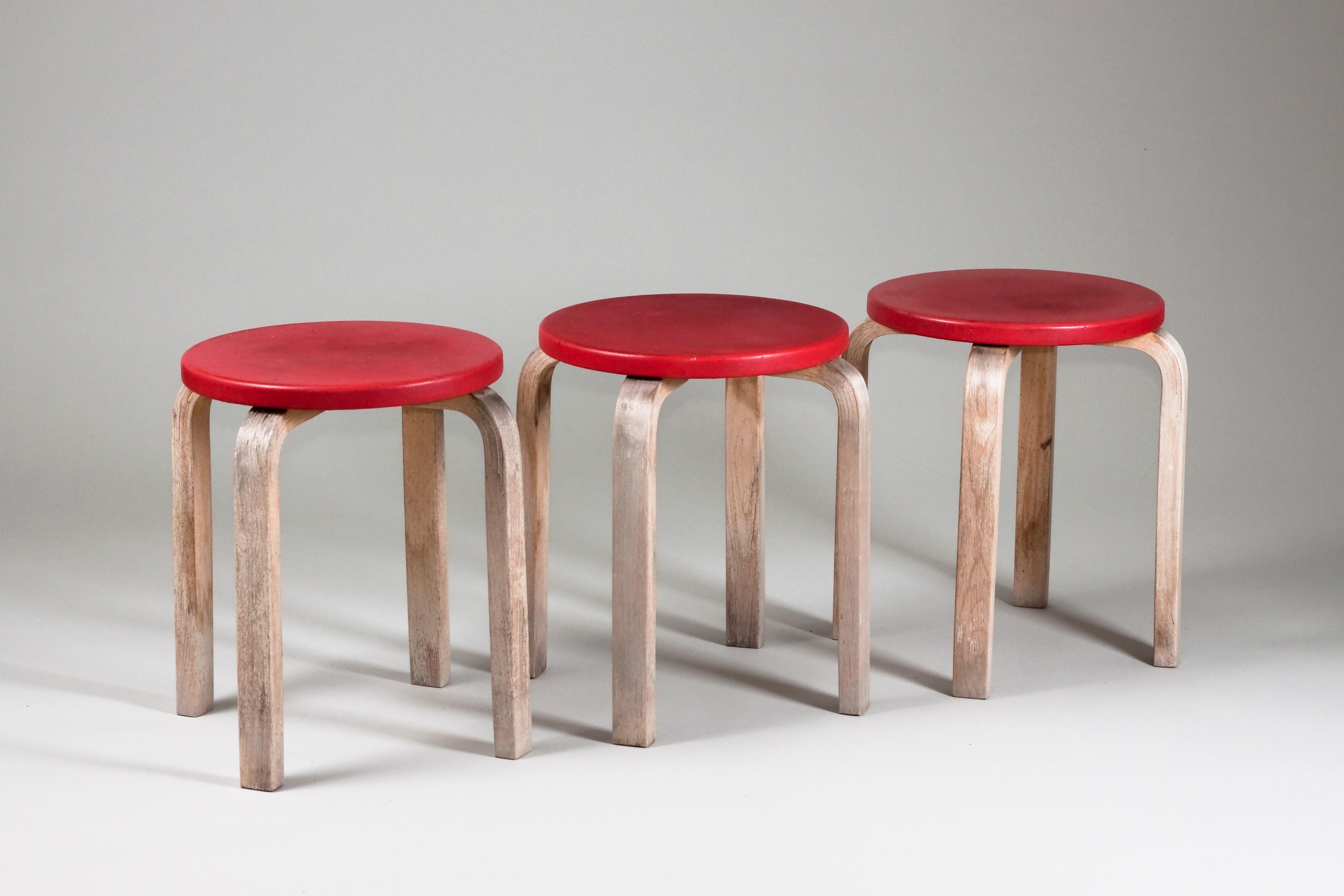 Set of three 1960s Alvar Aalto, E60 stools for Artek, upholstered in artificial red leather.