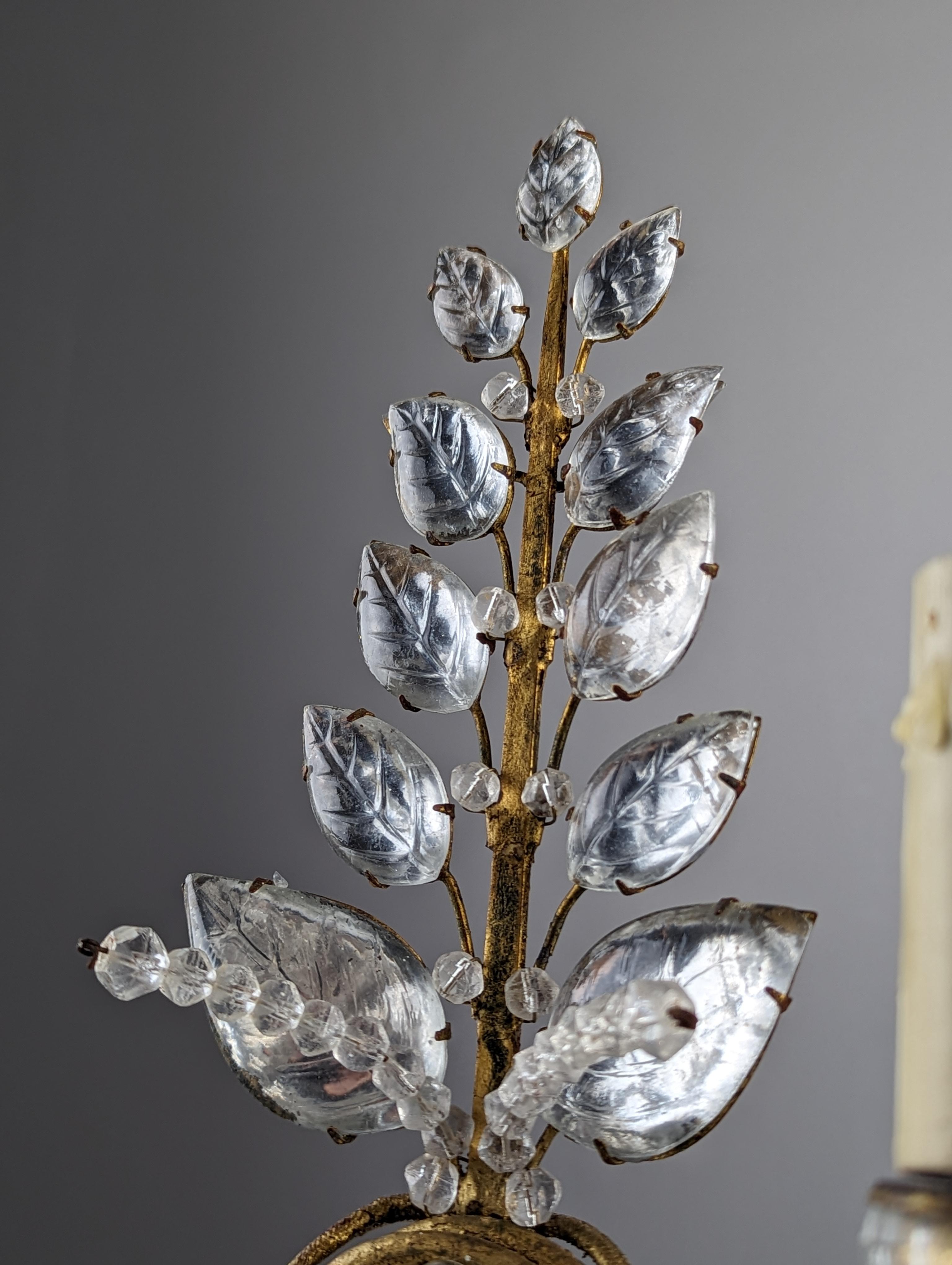 Beautiful set of three sconces attributed to Maison Baguès, produced in Paris, France at the beginning of the century showing the quality and craftsmanship of the prestigious French house. The crystal leaves delicately set in gold metal, two spikes