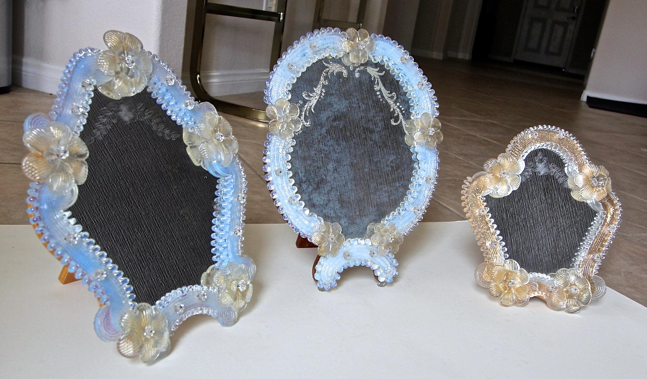 Grouping of three Italian Murano table mirrors with wood backing, some frames have opalescent glass and others clear glass with gold foil backing. All have clear and gold inclusion flowers. 
Sizes:
1) 10