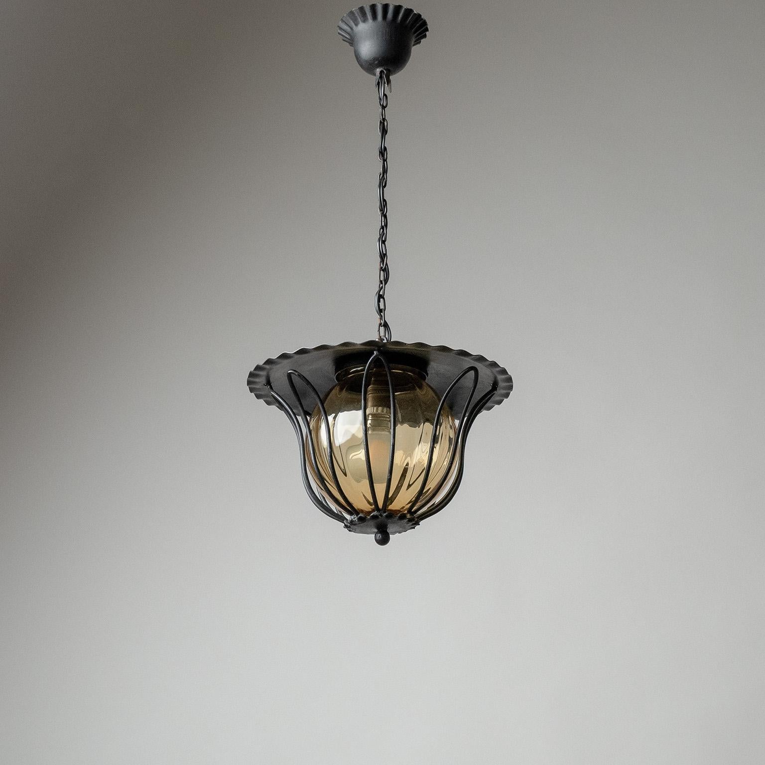 Charming set of three French iron lanterns from the 1950-1960s. Floral iron hardware with frilled edges and amber-colored blown glass diffusers. Nice original condition with some light age-related patina. One brass and ceramic E14 socket with new