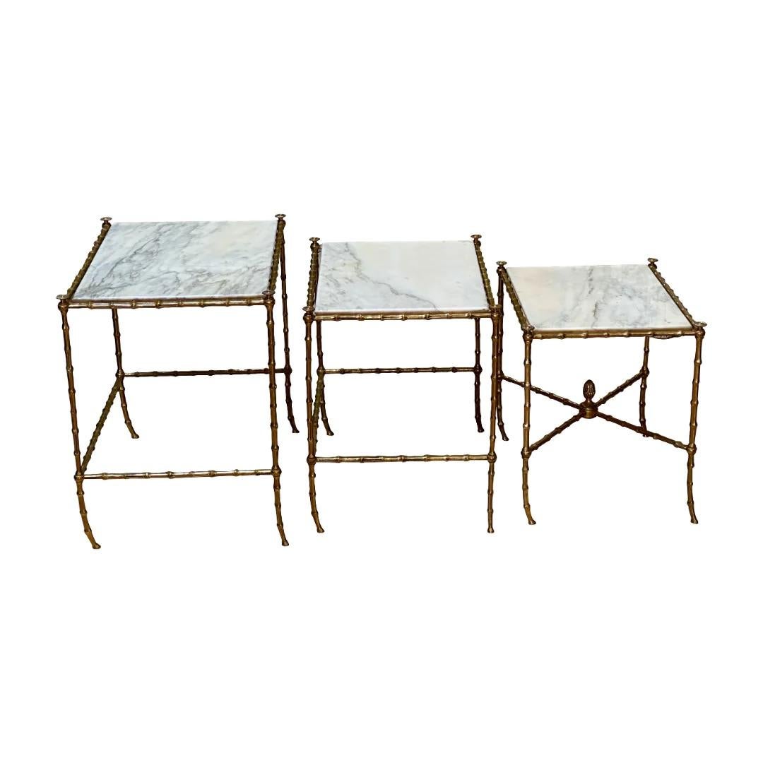 Set of three French Mid-century faux-bamboo brass and marble top nesting tables,likely Maison Jansen, created in France during the mid-century period, each of this set of three “tables gigognes” features a rectangular marble top set inside a brass