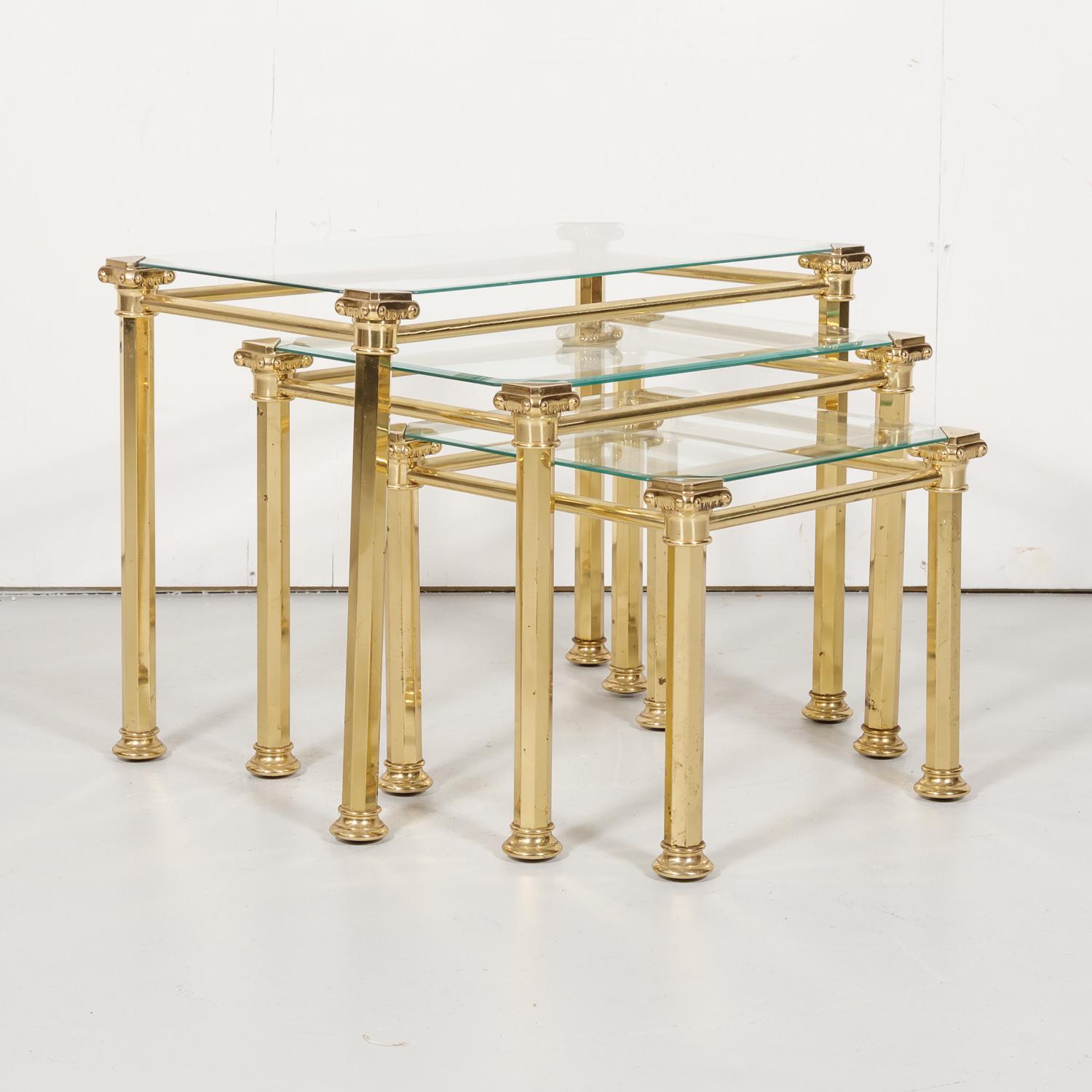 Very nice set of three midcentury French brass and glass nesting tables by prominent French design house Maison Baguès, having a brass capital at each corner with an inset glass top, circa 1950s. Raised on brass hexagonal legs that are joined by