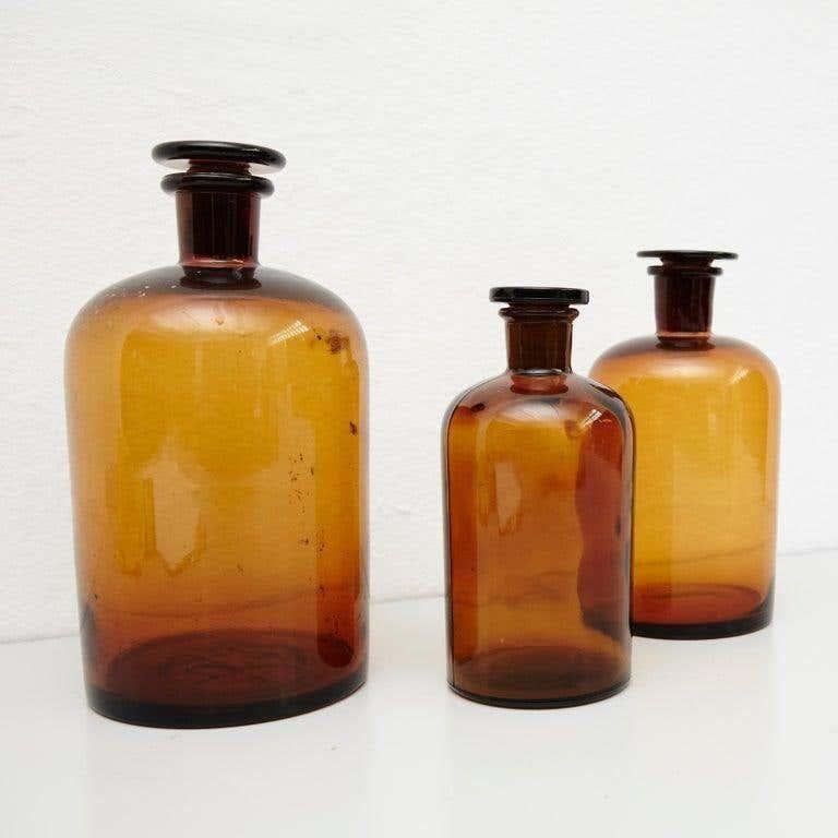 Set of three French vintage amber glass pharmacy bottle.  By unknown manufacturer, France, circa 1930.    In original condition, with minor wear consistent with age and use, preserving a beautiful patina.    Materials:  Amber glass    Dimensions: 