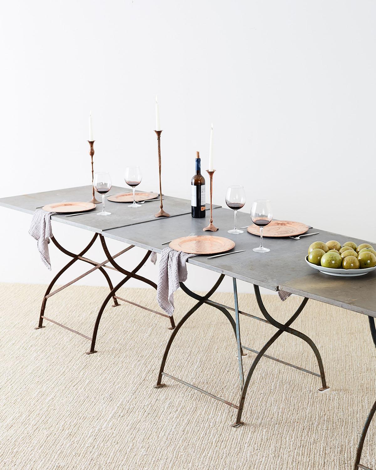 Rare set of three French zinc top garden tables featuring a bistro style folding iron base. These dining tables have beautifully aged soft zinc tops supported by an x base with campaign style folding legs. These dining tables work great on soft