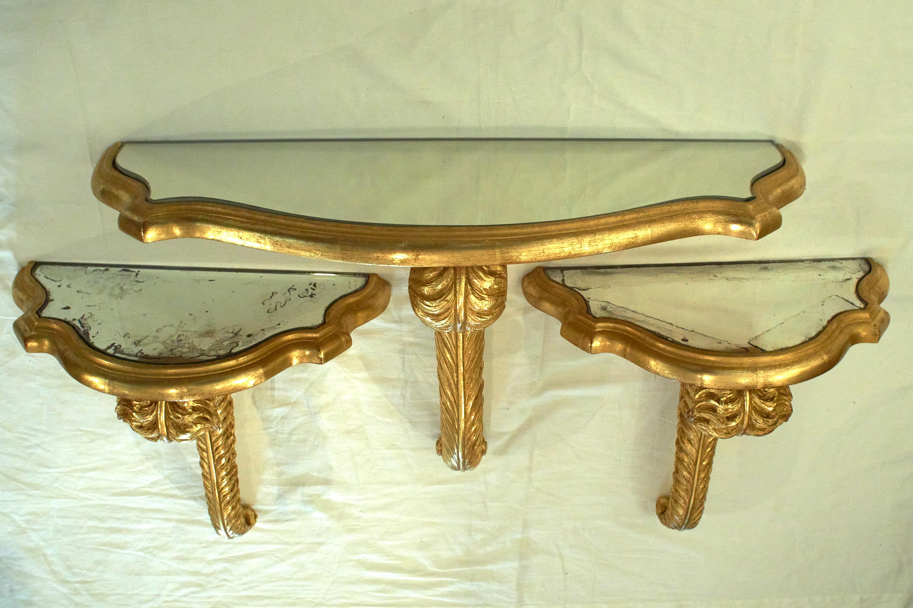 Set of wall brackets. Giltwood with carved feather plume motif and mirror top.

Measures: 1 Large shelf measures 32