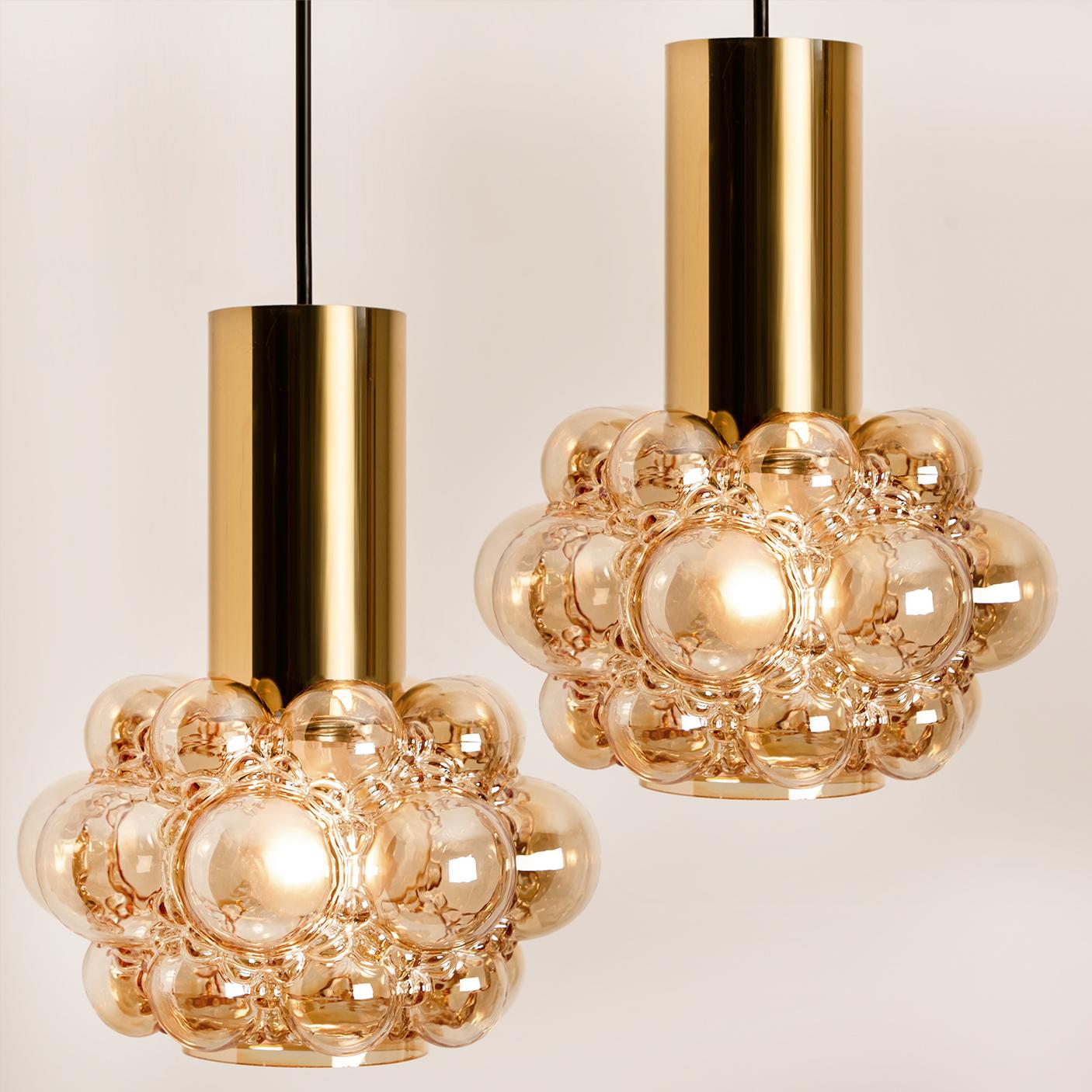 A pair of beautiful bubble glass chandeliers or pendant lights designed by Helena Tynell for Glashütte Limburg. A design classic, the amber colored/toned hand-blown glass gives a wonderful warm glow. 

Diameter: 9,8 in (25 cm). Height: Body without