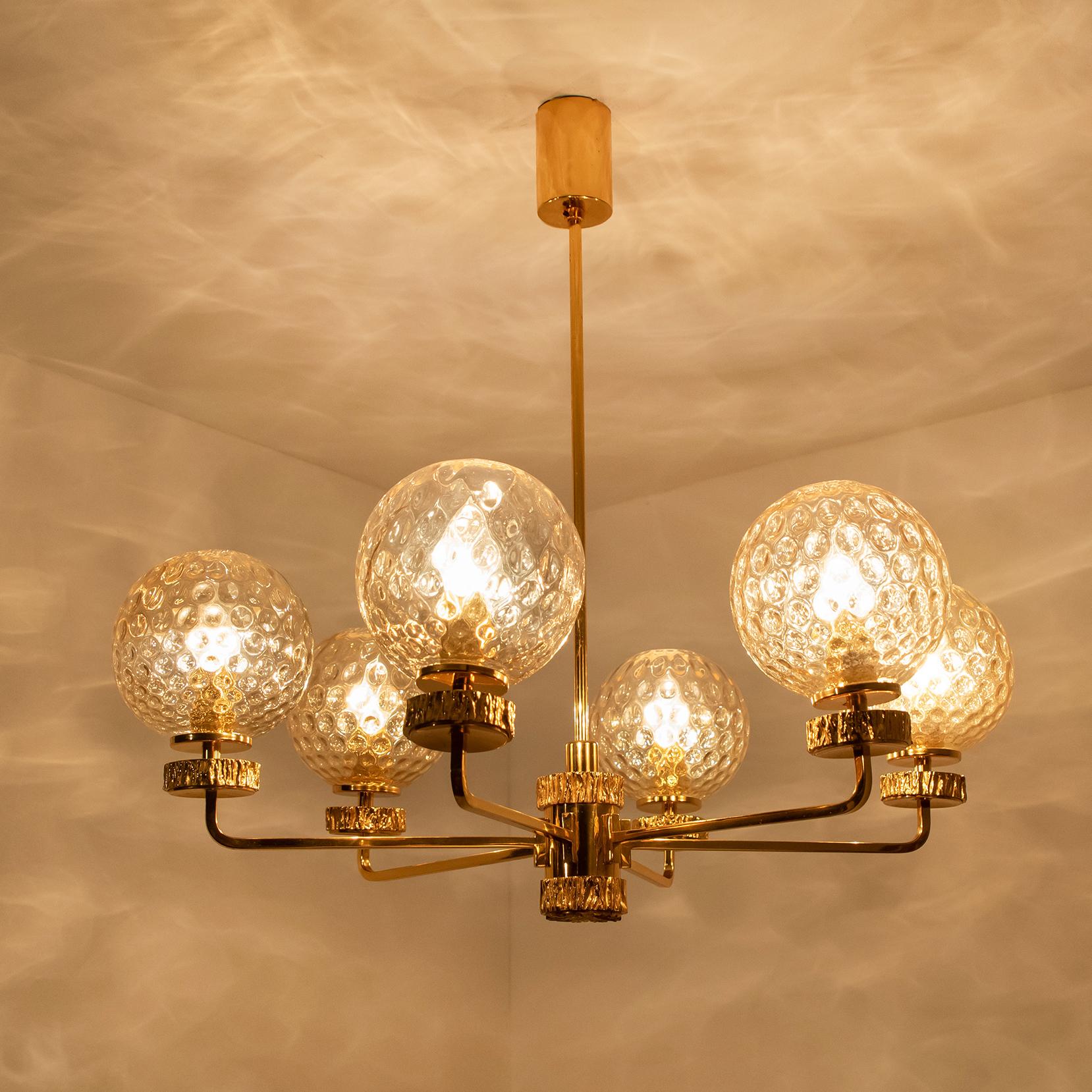 This stunning set light fixtures with textured glass bowls and gold-plated fittings was produced in the 1970s in the style of Brotto. Illuminates beautifully. Elegant and fine, it is comfortable with all decor periods.

This chandelier is large