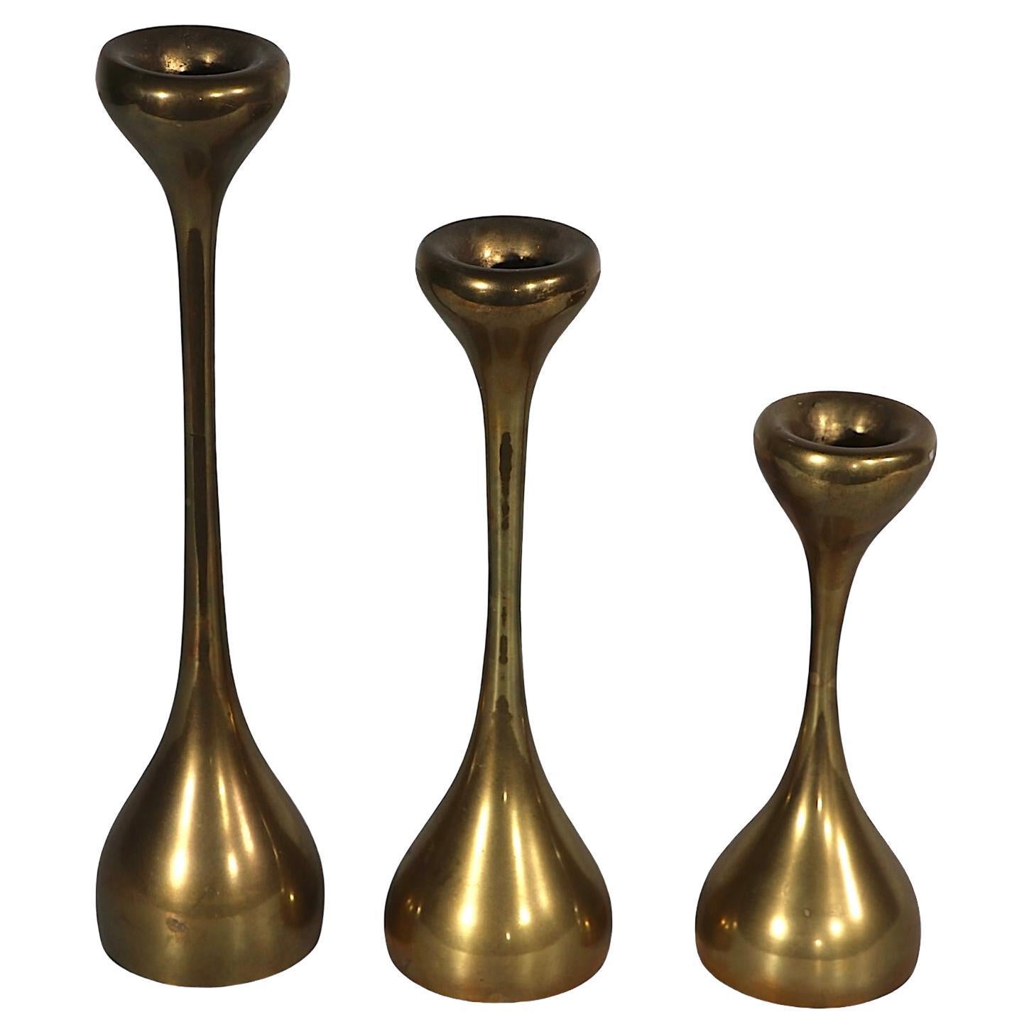 Elegant set of three Organic Modern candlesticks, having bulbous bases, elongated shafts, and  curvaceous candle cups. All three are in very fine, clean, original, ready to use condition. Possibly made in Denny, or Sweden, these examples are