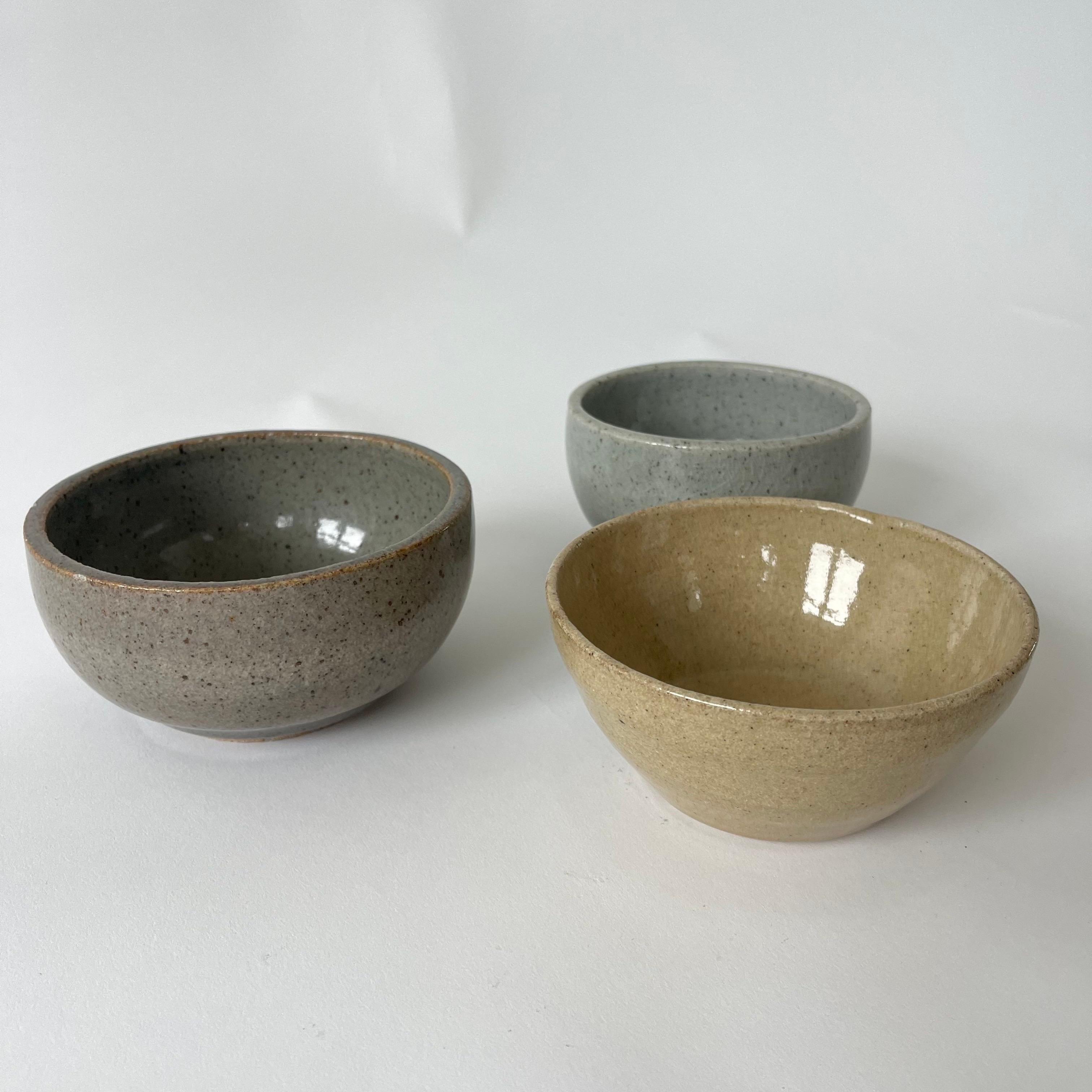 Collection de trois bols en poterie de studio, faits à la main, en terre cuite, émaillés en jaune, gris et bleu mouchetés.  Marqué sur le fond RL, USA, années 1960.