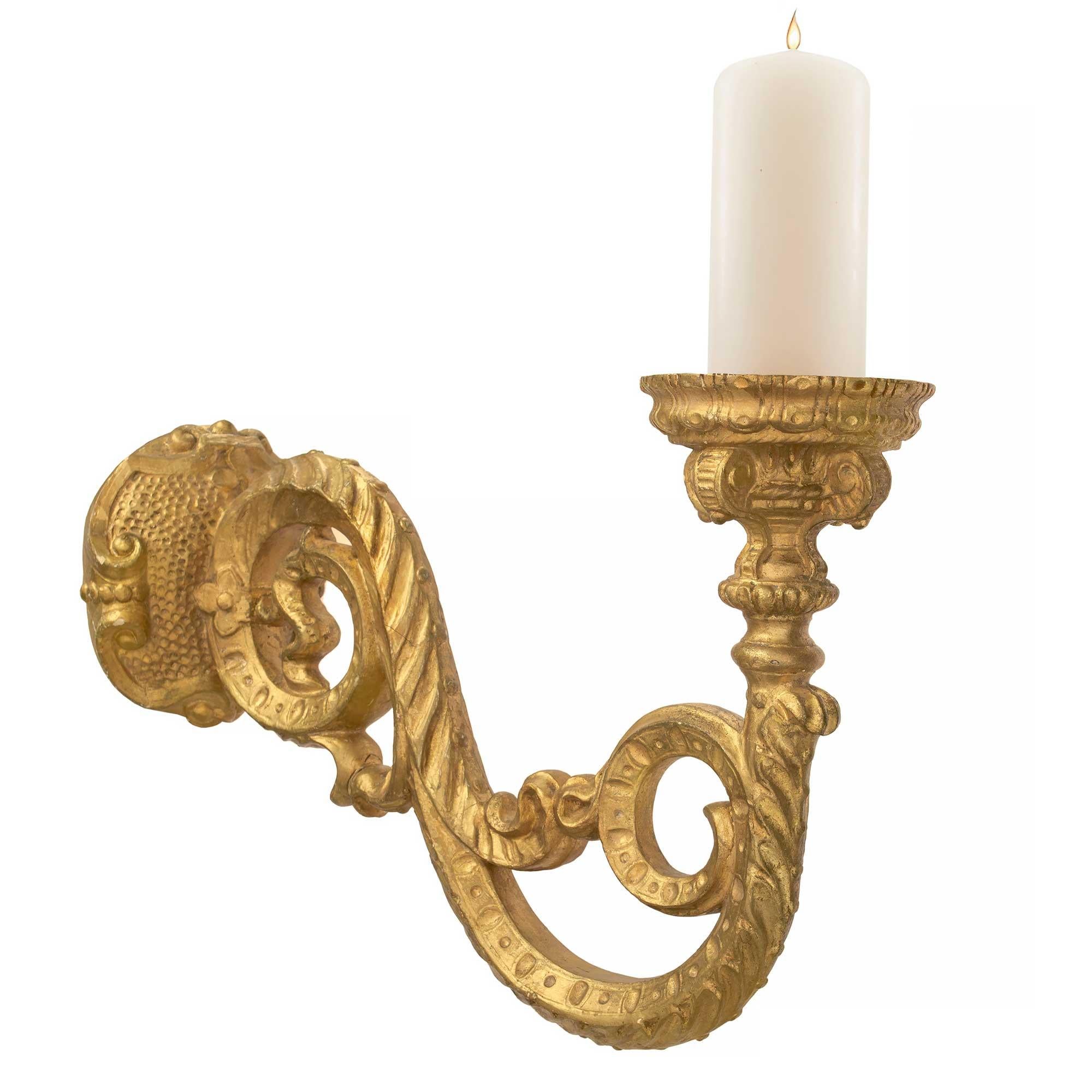 Llamativo y gran conjunto de tres apliques italianos de madera dorada del siglo XIX, estilo Luis XIV, Bras de Lumière. Los apliques presentan finas placas traseras martilladas y un elegante brazo central en forma de S, con diseños foliados ricamente