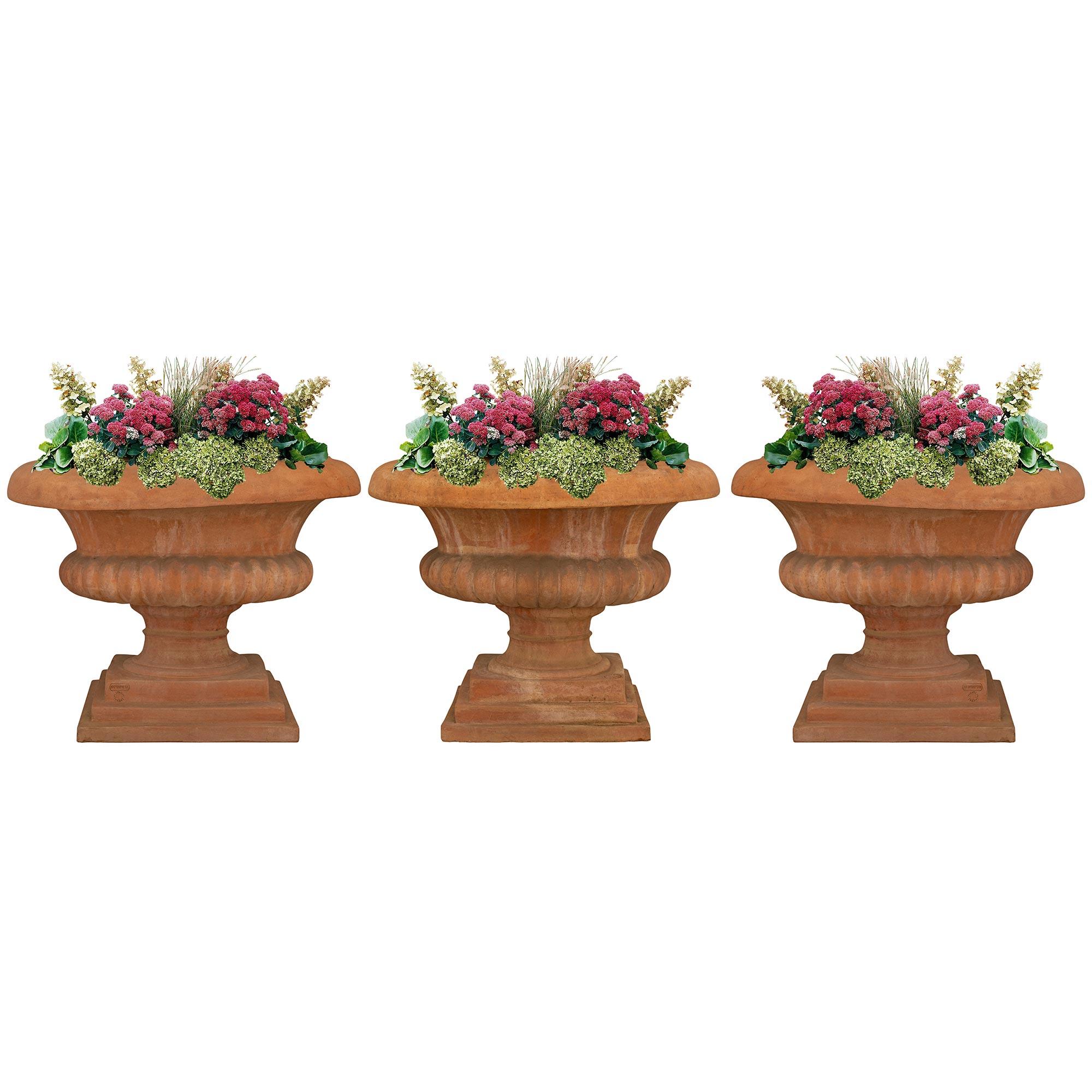 Bonito juego de tres maceteros de terracota romana italiana del siglo XIX. Cada urna ovalada de gran escala se eleva sobre finas bases rectangulares bajo los soportes del pedestal en forma de zócalo ligeramente curvado. Los cuerpos de arriba