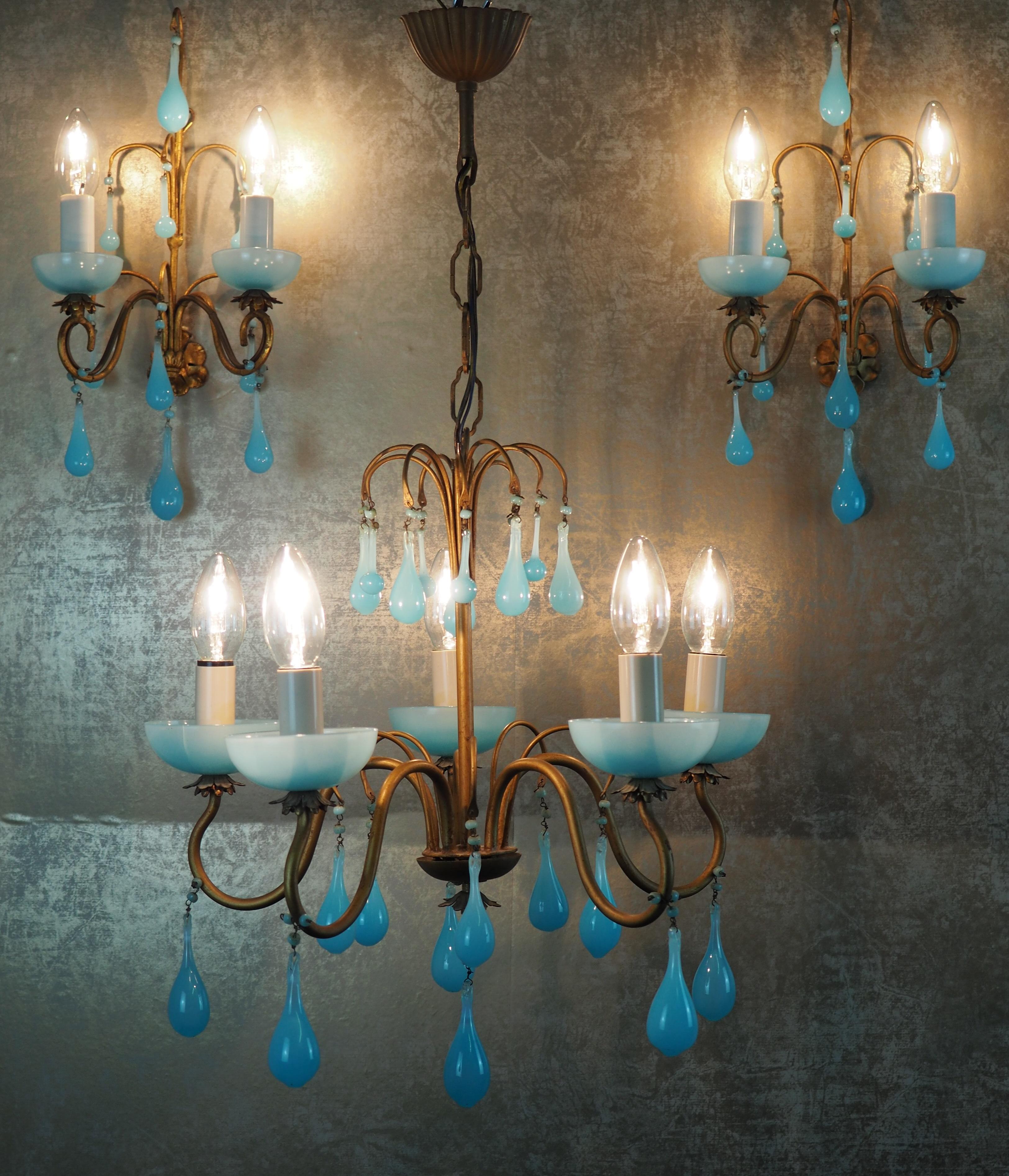 A wonderful set of three aqua opaline blue light fixtures, Italy, circa 1950s.
This beautiful handcrafted chandelier and sconces are made of patinated metal decorated with opaline blue Murano drops.
Socket: e 14 for standard screw