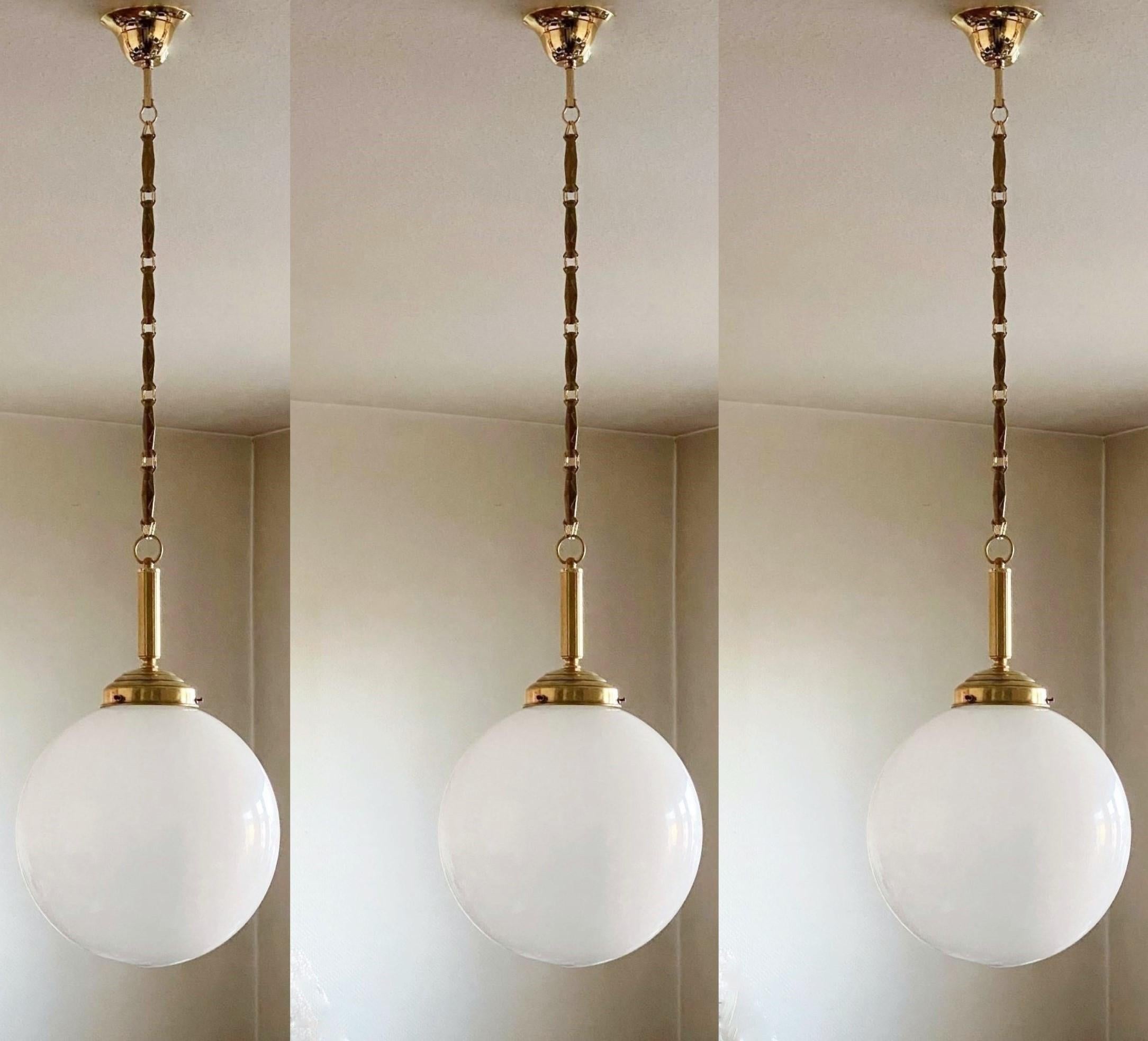 A set of three hand blown opaline glass ball pendant with brass mounts, chain and canopy, Italy, 1940s.
One porcelain Edison E-27 light socket for a large sized screw bulb up to 100W.
Measures: Diameter 12