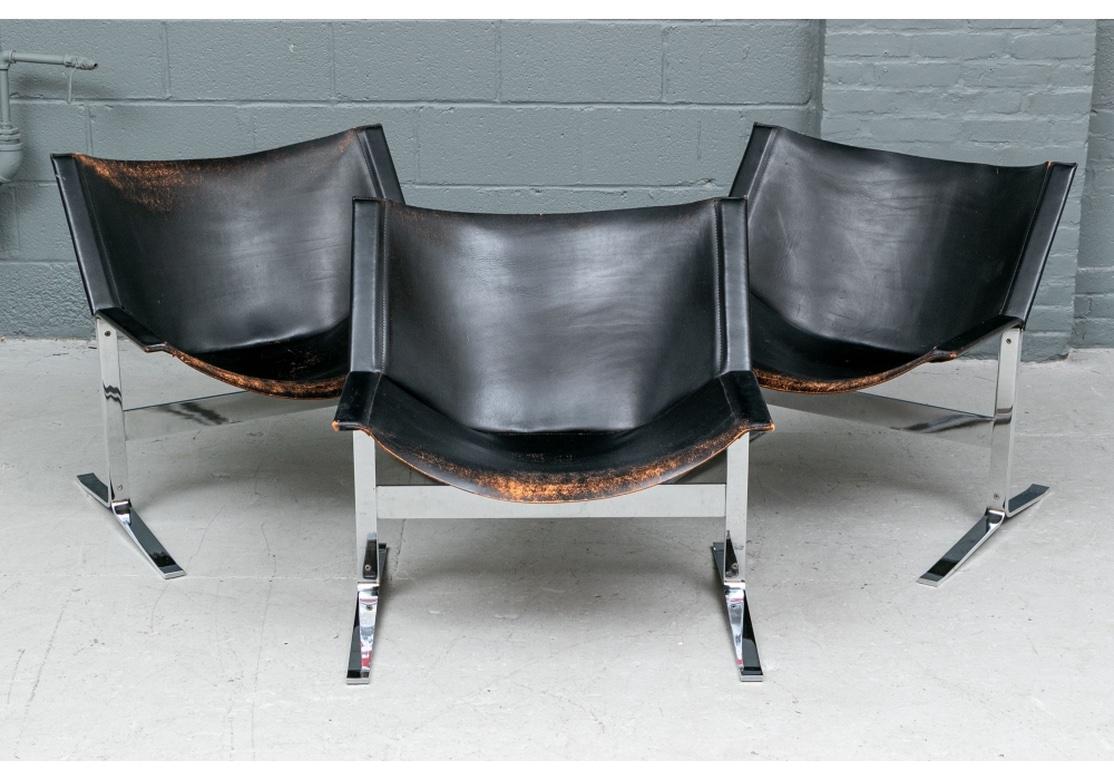 Classic Italian mid century style lounge chairs with cantilever form and having heavy chromed steel bases. Fine modern Italian black leather sling chairs with chrome bases. With curved backs and deep seats, mounted on the chrome bases with