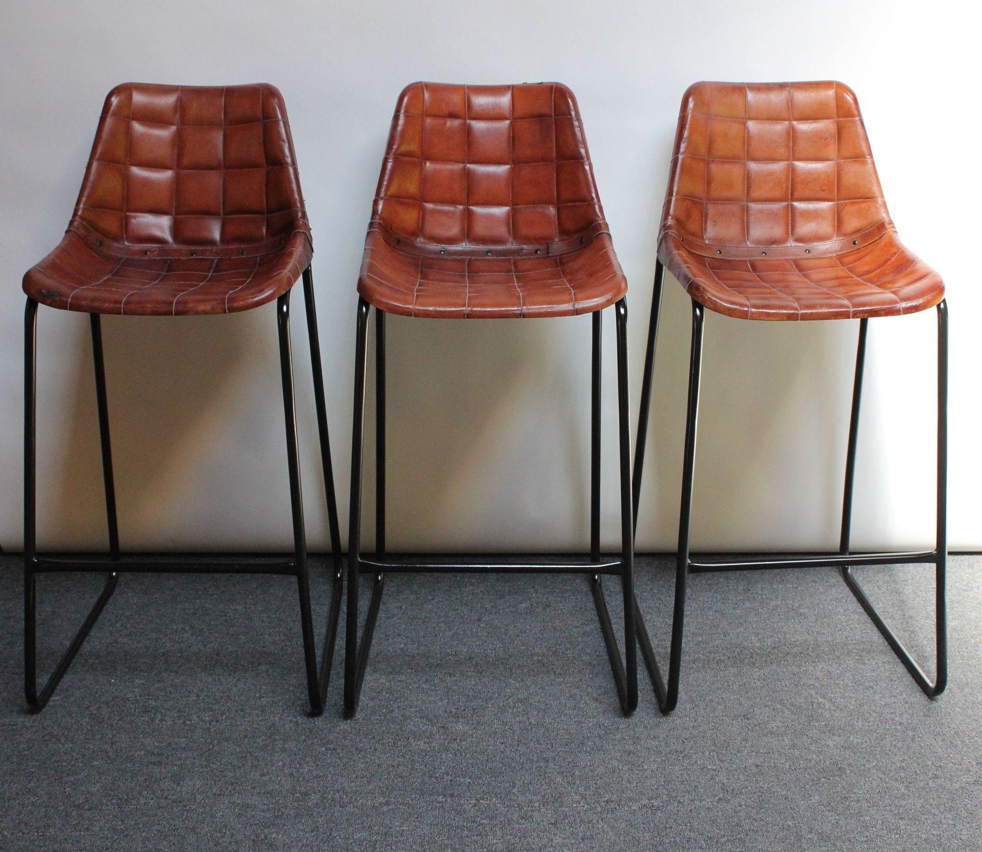 Set of three richly patinated barstools with leatherette seats supported by wrought iron and steel frames with footrests (ca. 1970s, Italy).
Though the maker is unknown, contemporary adaptations of these stools have been made within the last several