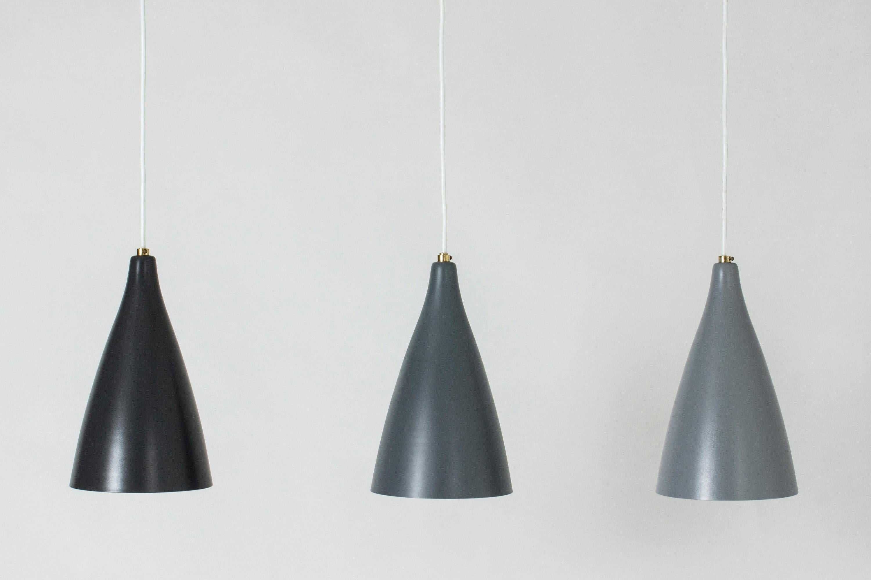 Set of three lacquered metal ceiling lamps from Böhlmarks, in three nuances of grey. Clean design with a small brass detail on top. Can be suspended at different heights.