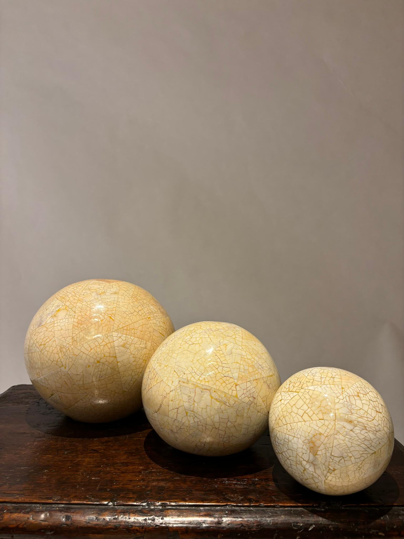 Set of three graduated spheres with a wonderful eggshell lacquered finish in a triangular patterns. Clearly hand carved, none are exact spheres which only adds to their charm. This and the gradations in color create a singular decorative appeal. 
8