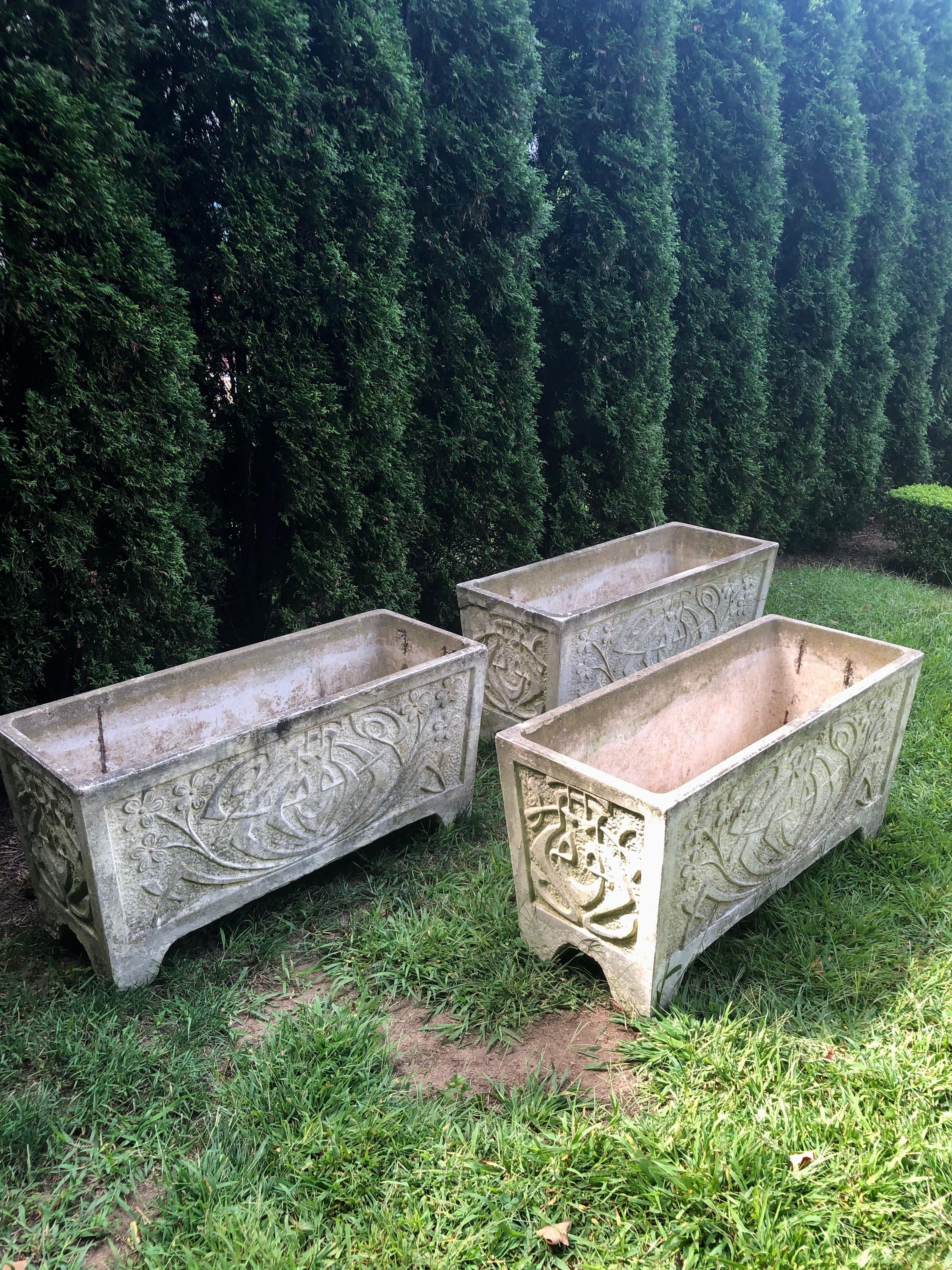 This set of three large cast stone planters is quite heavy and have an elegant form. They have a lovely Art Nouveau style and are sufficiently large to house a plethora of blooms or small boxwoods. In very good condition overall, there are some