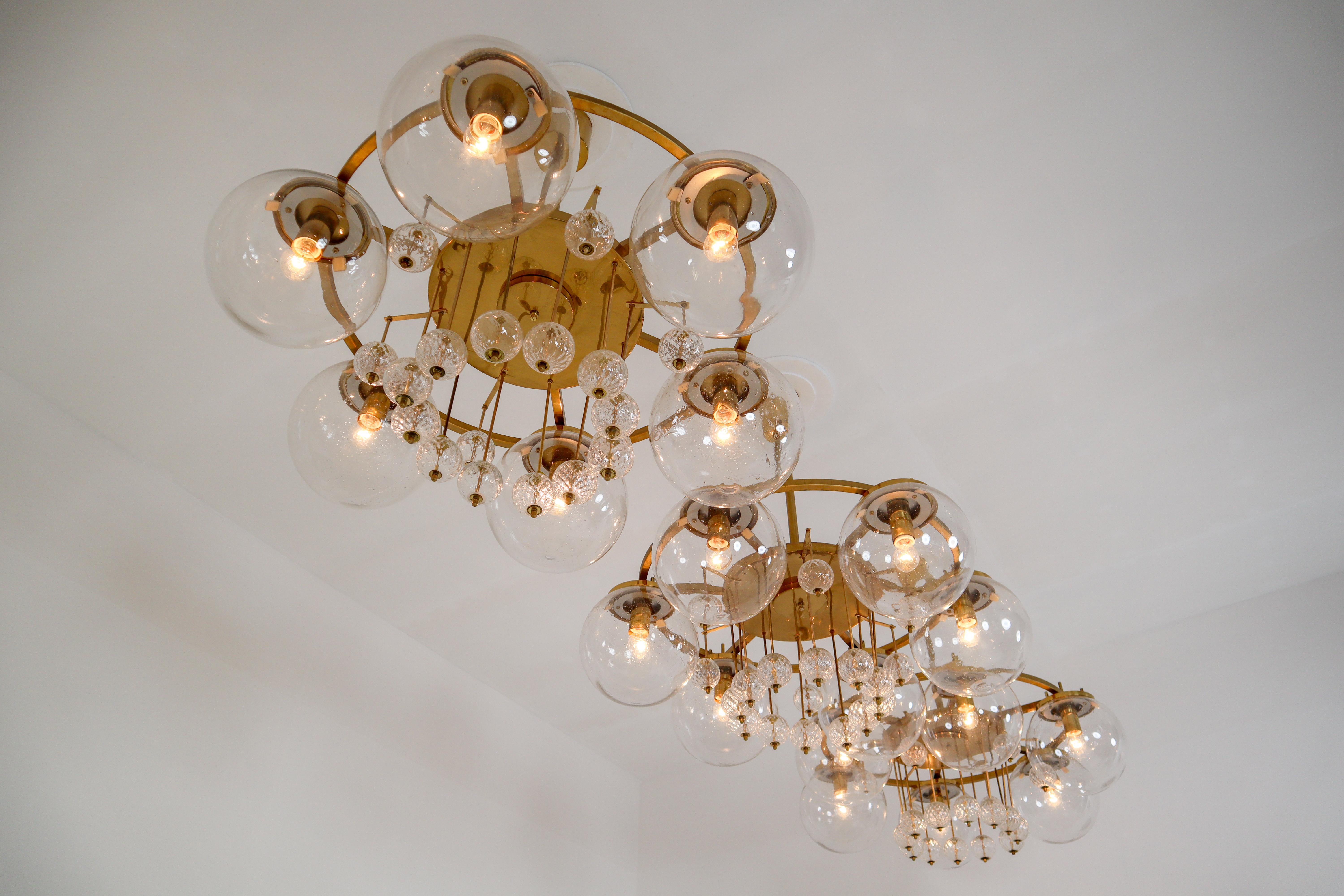 Large hotel chandeliers with brass fixture and large hand blowed glass. The chandeliers with brass frame consist of six lights, formed in a circle, with glass shades. The pleasant light it spreads is very atmospheric. Completed with the structured
