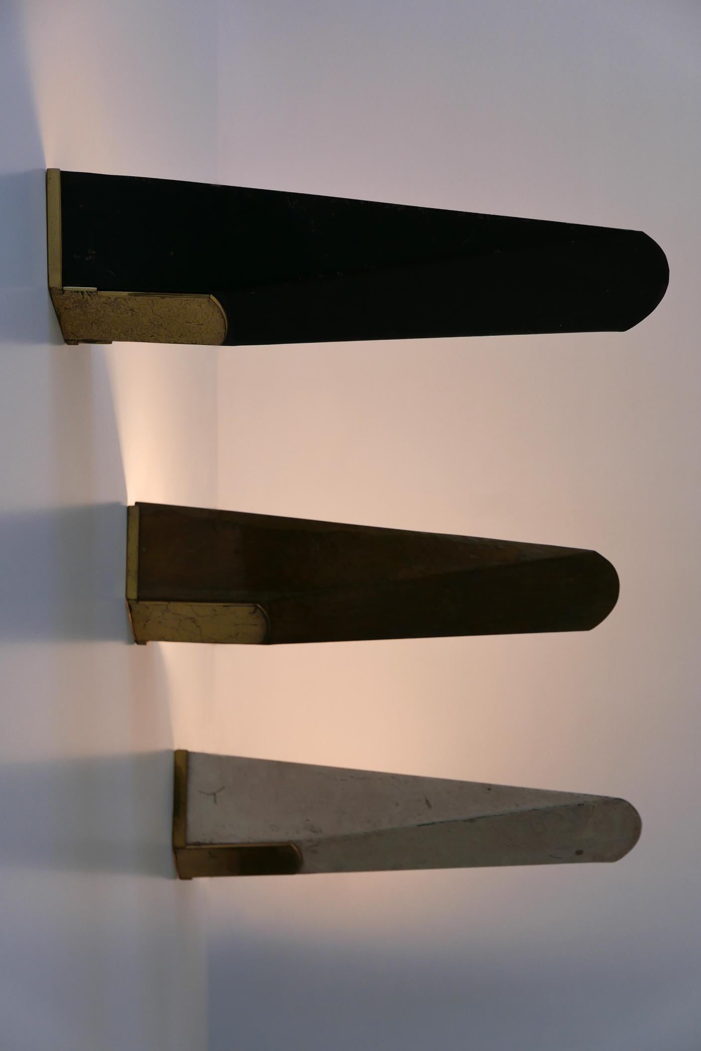 Satz von drei großen und eleganten Mid-Century Modern Wandlampen oder Wandleuchter. Entworfen und hergestellt wahrscheinlich in den 1950er Jahren in Deutschland. 

Ausgeführt in Metall/Messing, benötigt jede Lampe 1 x E27 / E26 Edison-Schraube fit